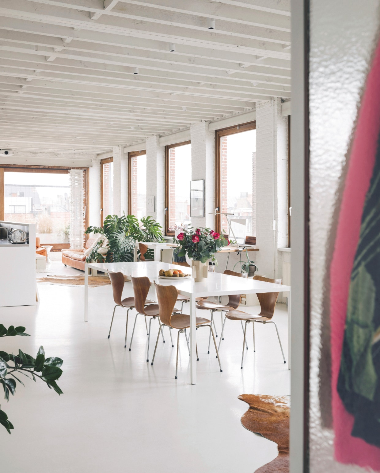 In de oude balkenstructuur zitten Medard-spots van Modular verwerkt. De bureaulamp is de Acus Office lamp van Betec. De planten zijn een toevoeging van Raphaël, die vier jaar geleden vanuit Parijs introk in de loft. De witte hoogglans keuken gaat op in de minimalistische, industriële architectuur. Het inox keukenwerkblad en de inox toaster zorgen voor een accent. Stijlvol Wonen 05-2025 | fotografie Katoo Peeters