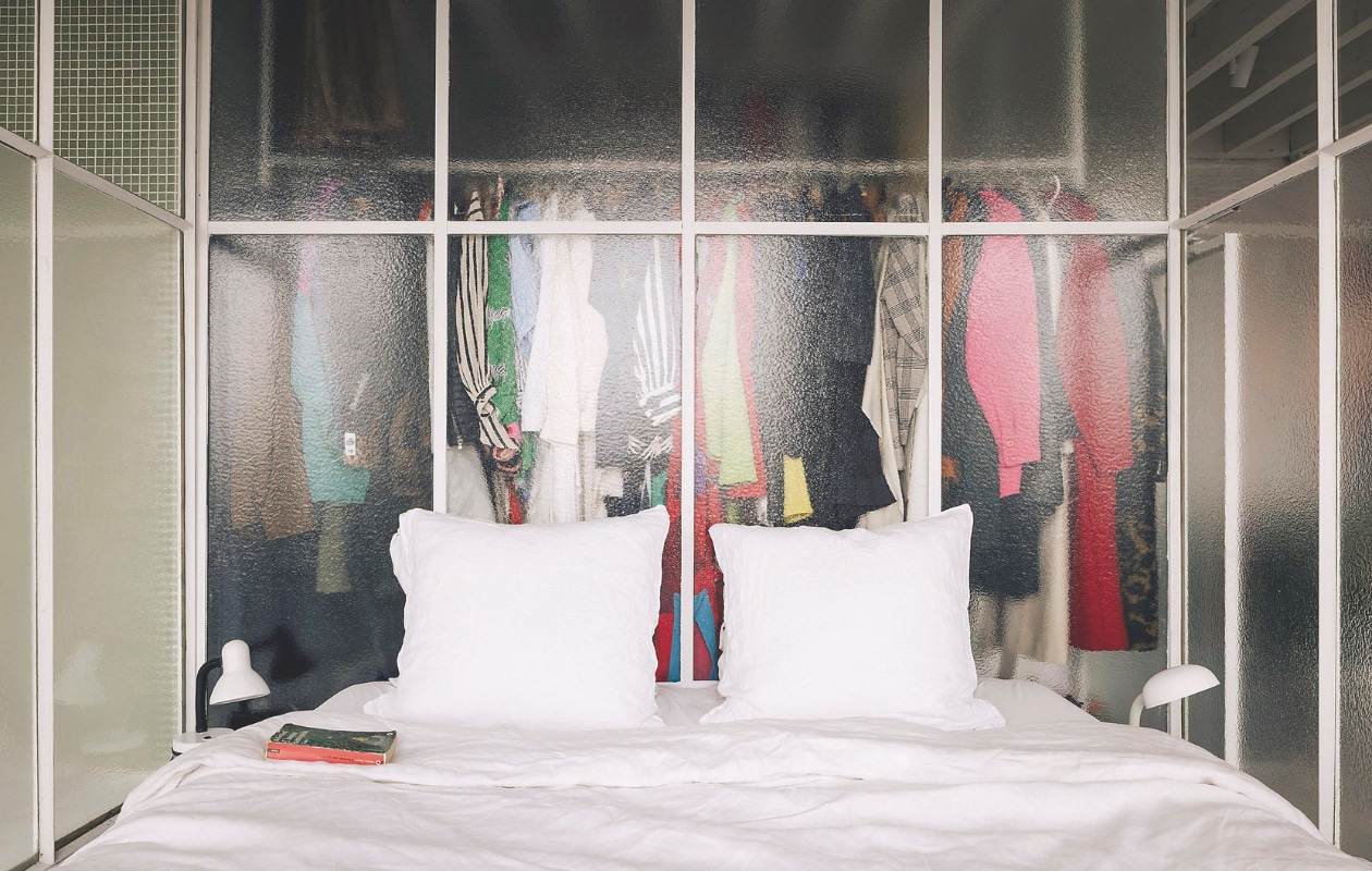 Doordat de slaapkamer best klein is, zijn er overal kasten onder verwerkt. De zichtbare kleding voegt kleur toe. De slaapkamer, dressing en badkamer zijn afgezonderd met schuifpanelen uit semitransparant glas. Daardoor blijven alle delen van de loft met elkaar verbonden. Stijlvol Wonen 05-2025 | fotografie Katoo Peeters