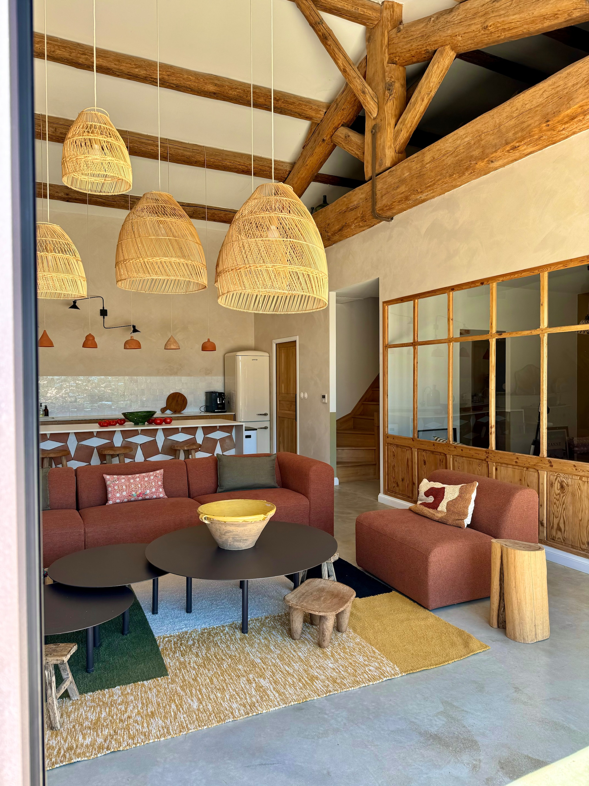 anken By Sidde, metalen salontafels zelfgemaakt, katoenen kleed Saudade Design. Fauteuil Rua Madeira, rotan stoelen PK22 van Poul Kjaerholm voor Fritz Hansen. Travertin bijzettafel Talka. Groene installatie gemaakt van schijnhulst. vtwonen 07-2025 | fotografie Manon Ferra