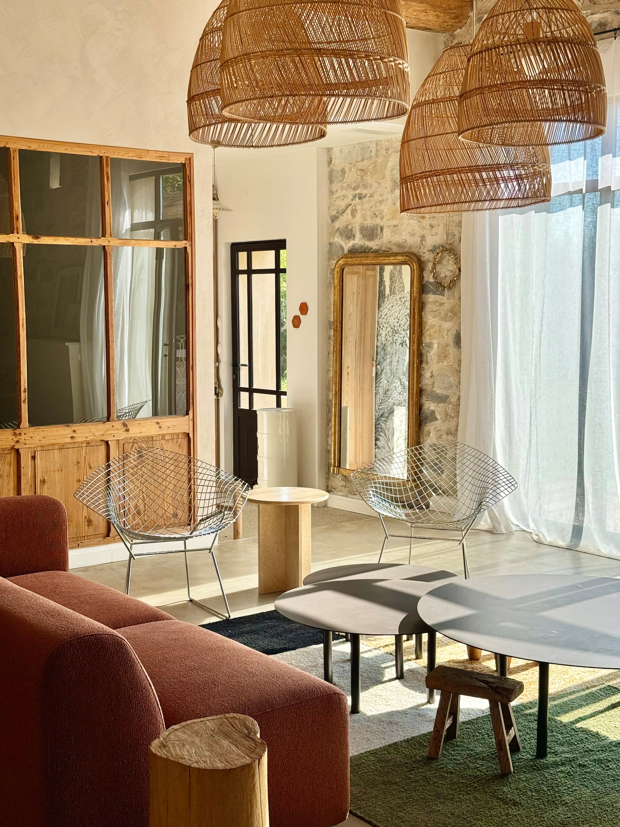 anken By Sidde, metalen salontafels zelfgemaakt, katoenen kleed Saudade Design. Fauteuil Rua Madeira, rotan stoelen PK22 van Poul Kjaerholm voor Fritz Hansen. Travertin bijzettafel Talka. Groene installatie gemaakt van schijnhulst. vtwonen 07-2025 | fotografie Manon Ferra