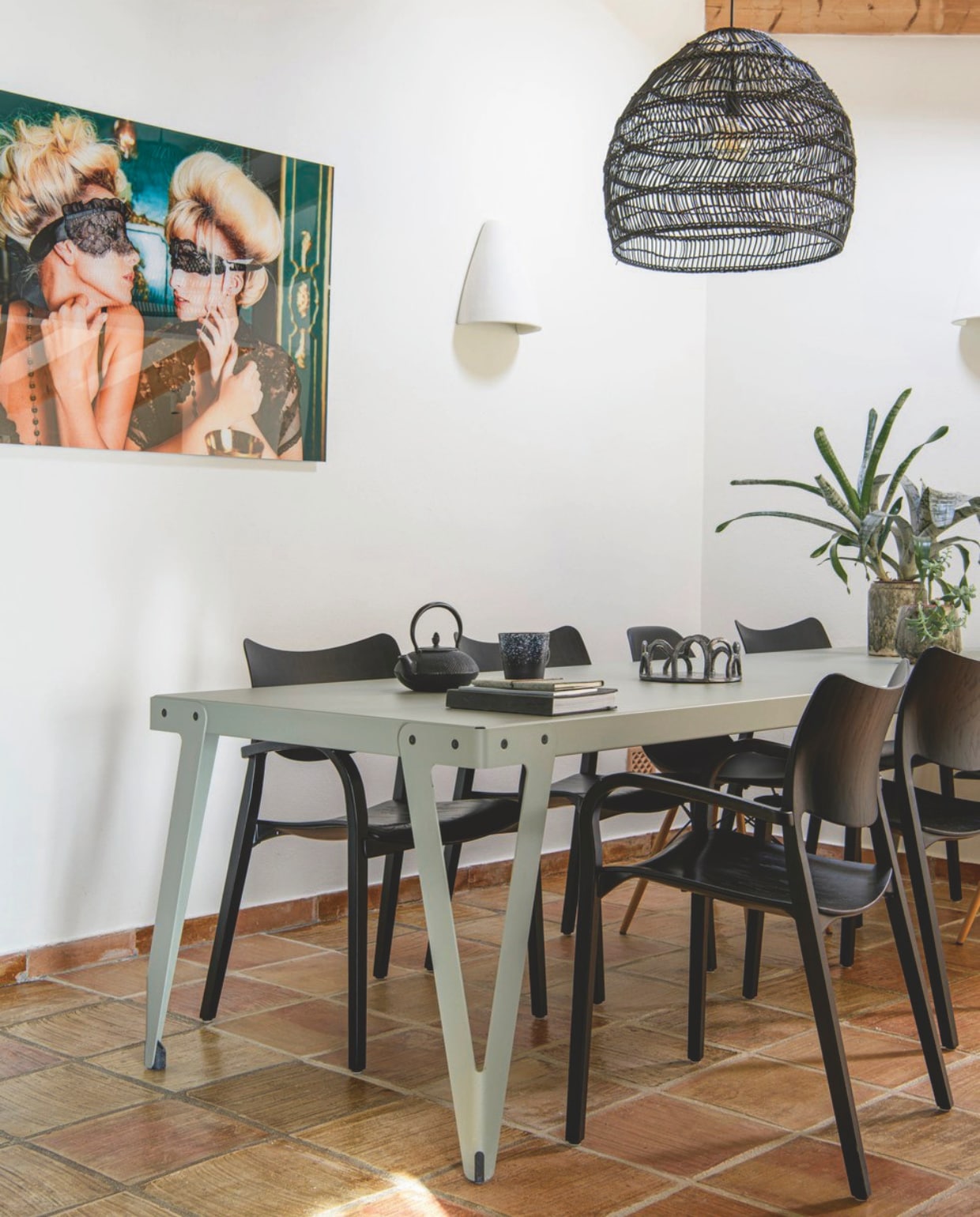 Tafel Lloyd van Functionals. Zwarte houten stoelen Stua. Zwarte kunststof stoelen Vitra. Lamp en theemok HKliving. Foto Jordi Gomez via Cobra Art. Fruitschaal zelfgemaakt. Gietijzeren theepot onbekend. Vloer originele vloer uit de finca. Wandlamp (teja) van lokaal keramiekbedrijf. vtwonen zomerboek 2025 | styling Inge van Lieshout | fotografie Louis Lemaire