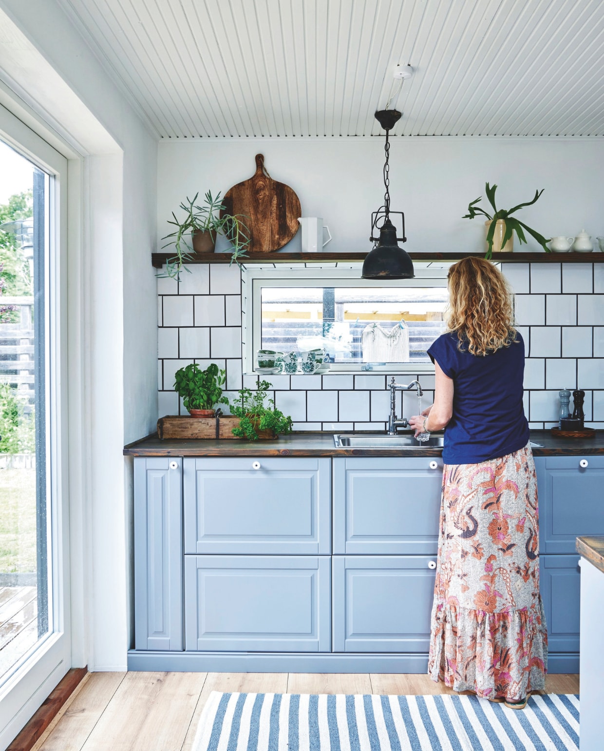 Keuken Ikea. Het aanrecht en de plank erboven zijn  gemaakt van oude grenen vloerplanken. Ze zijn geolied in een donkerbruine kleur. Hanglamp van Chic Antique en vloerkleed Vitrinen. vtwonen landelijk 04-2025 | Styling Rikke Graff Juel | Fotografie Anitta Behrendt