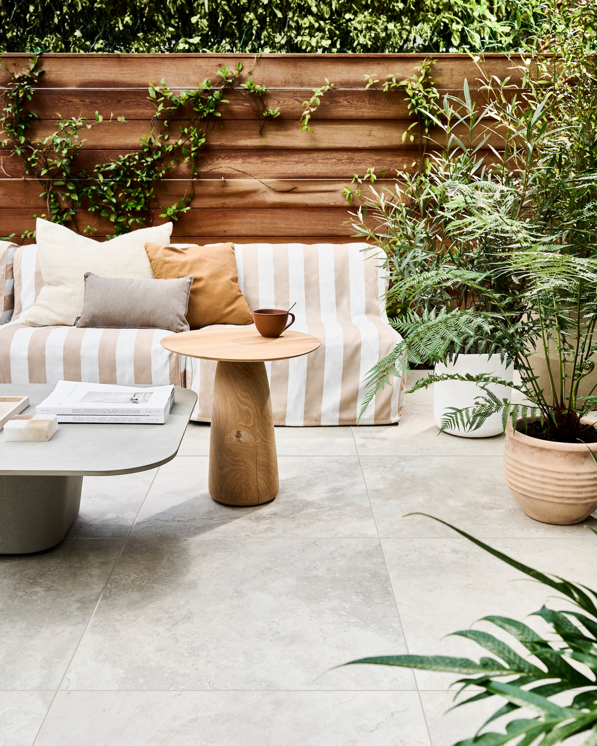 Tuintegel Solostone Uni Dust Off White, 70x70 cm, per m² € 74,50. M.m.v. basiclabel.nl (opblaasbare fauteuils Sit on Air van vtwonen), dacks.nl (salontafel, bijzettafel), intratuin.nl (terracotta bloempotten, groot bruin kussen, klein bruin kussen), vtwonen.nl/shop (witte bloempot van Serax), zarahome.com (travertin plateau). Overig privébezit. vtwonen 05-2024 | styling Marlies Does | fotografie Sjoerd Eickmans