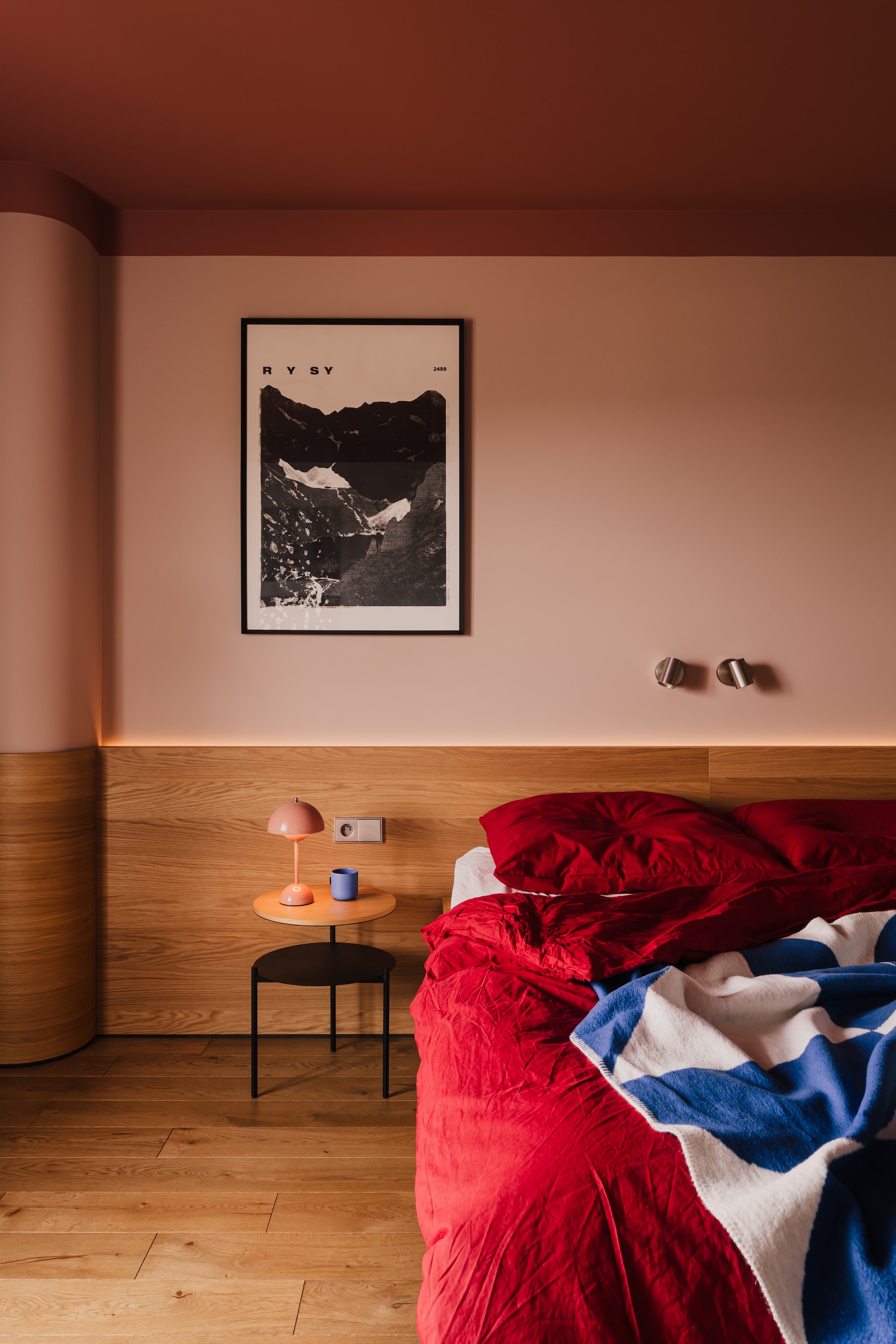 De slaapkamer met gebogen houten lambrisering en sfeervol terra plafond. Het blauwe dressoir is speciaal ontworpen om te harmoniëren met andere blauwe accenten in het interieur. Hanglamp en tafellamp Flowerpot van &tradition. Bedsprei Tul Throw van Noo.ma. stijlvol wonen 7-2025 | productie Kubieniec + Dlugosz | fotografie Zasoby Studio