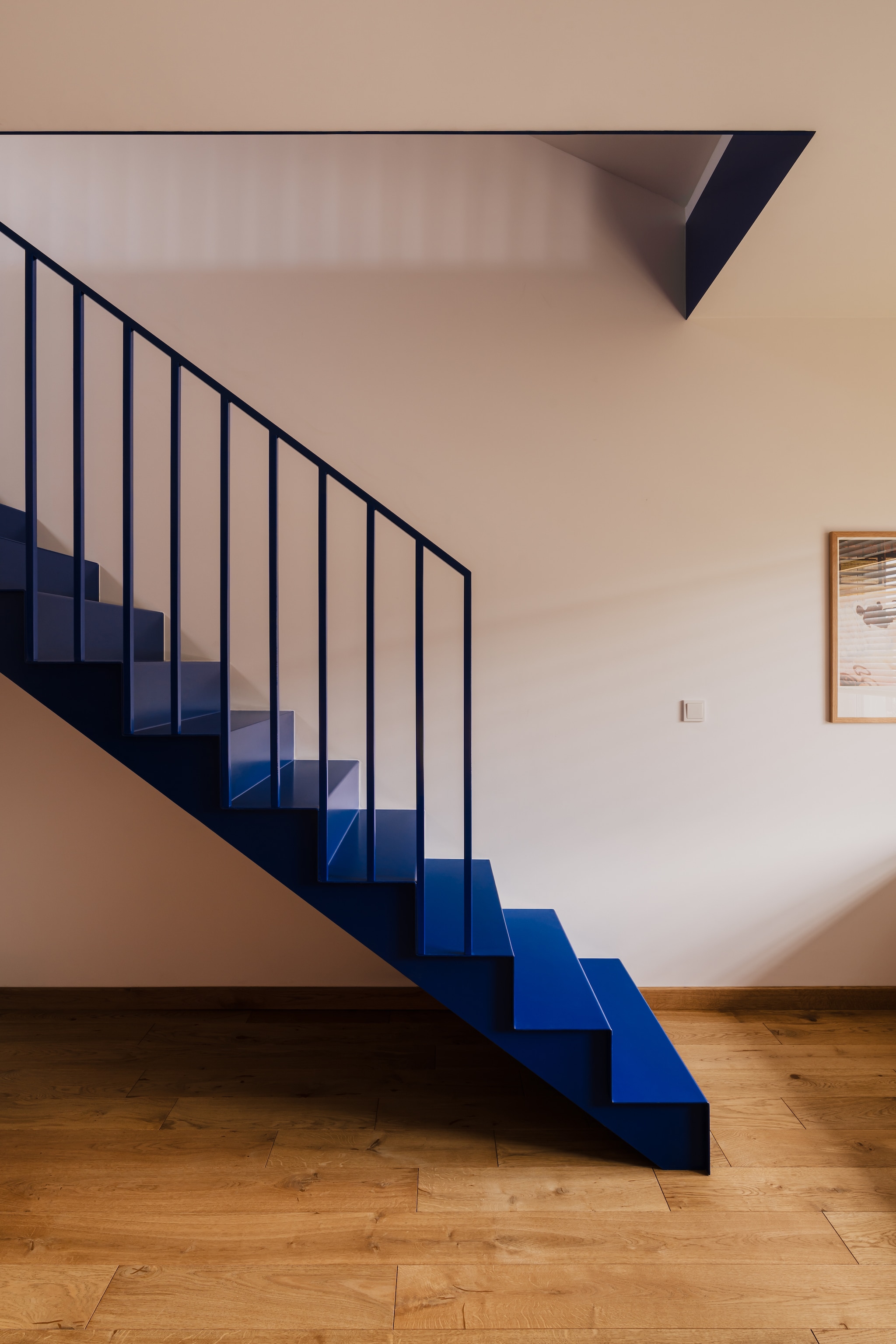 De kobaltblauwe stalen trap creëert verschillende interessante grafische accenten in deze ruimte. stijlvol wonen 7-2025 | productie Kubieniec + Dlugosz | fotografie Zasoby Studio