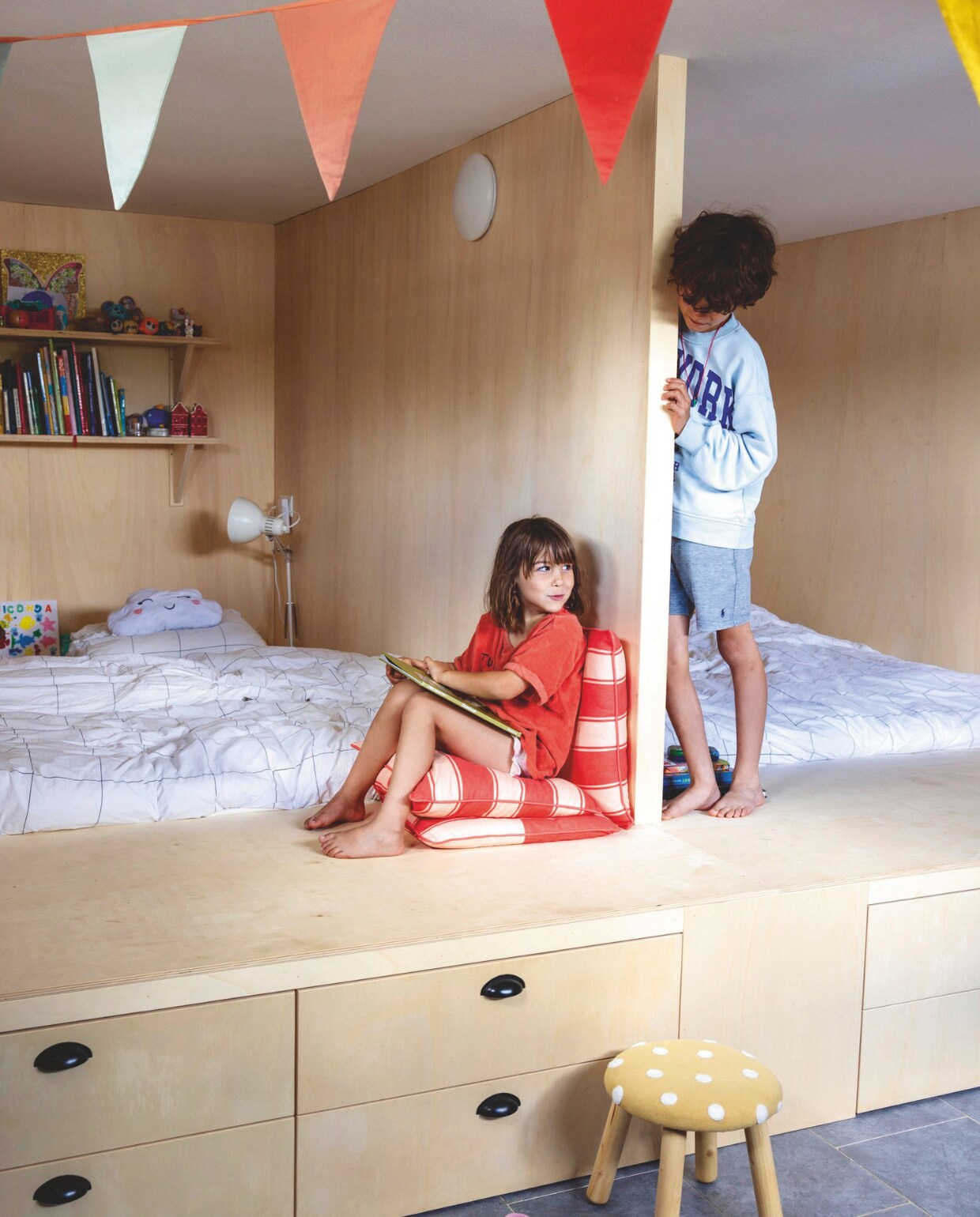 Bedstee op maat gemaakt door timmerman. Vlaggetjes Dille &amp; Kamille. Rode kussens Zeeman. Beddengoed Wehkamp. Kruk Kwantum. vtwonen 05-2025 | styling Ilona Jongepier | fotografie Dana van Leeuwen | tekst Chris Muyres