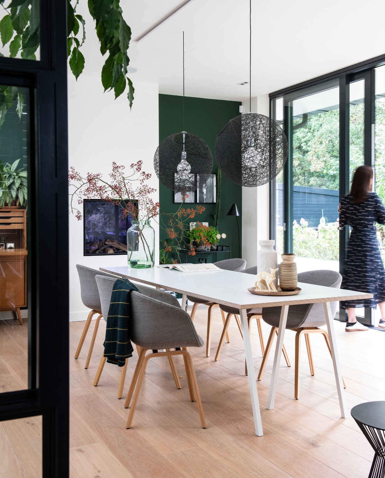 De tuinkamer met ‘de stamtafel’ van Hay. Eikenhouten vloer van Dirkedaen. Stoelen Hay, zwarte hanglampen Moooi. Vintage vazen, gekocht in diverse curiosawinkels. Hertjes vintage design uit de jaren 70. Vintage vaas van West Germany. Zwarte trolley en vloerlamp House Doctor. Groene verf van Histor. Illustratie van Geertje Aalders. vtwonen 05-2019 | styling Inge van Lieshout, Inside Homepage | fotografie Louis Lemaire, Inside Homepage