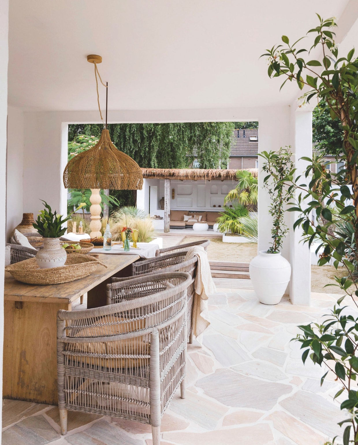Rotan stoelen, tafel, manden, vazen, plaid, rotan open bloemlamp en vaas Legian white Coco homeliving. Terrasvloer Brazil Yellow Flagstones Van den Heuvel &amp; Van Duuren. vtwonen special zomerboek 12-2025 | fotografie Corine Hoge Bavel-Jansen | tekst Caroline Westdijk