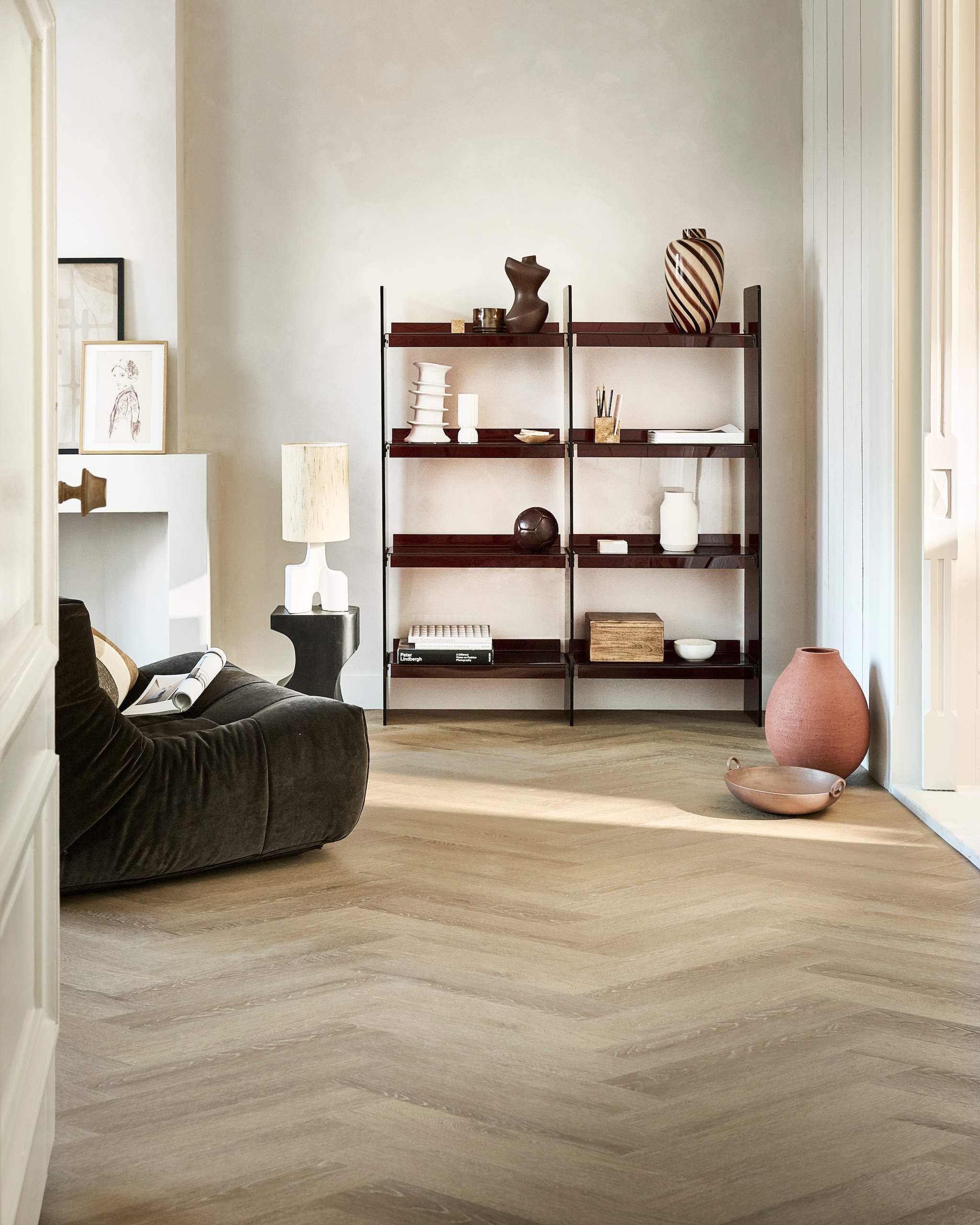 Pvc-vloer Noble in Sunkissed, gelegd in Weense punt, 53,8x11,7 cm, dryback per m² € 48,95.M.m.v. hkliving.com (wandkast, zitelement, gestreepte vaas, kussen, vloerkleed), urbannatureculture.com (bijzettafel, tafellamp, bruin object, kistje, houten doos, schaal), tinystories.nl (print), vtwonen.nl/shop (ribbelvaas van Serax, organizer van Ferm Living), zarahome.com (terracotta vaas). vtwonen 08-2024 | styling Marlies Does | fotografie Sjoerd Eickmans