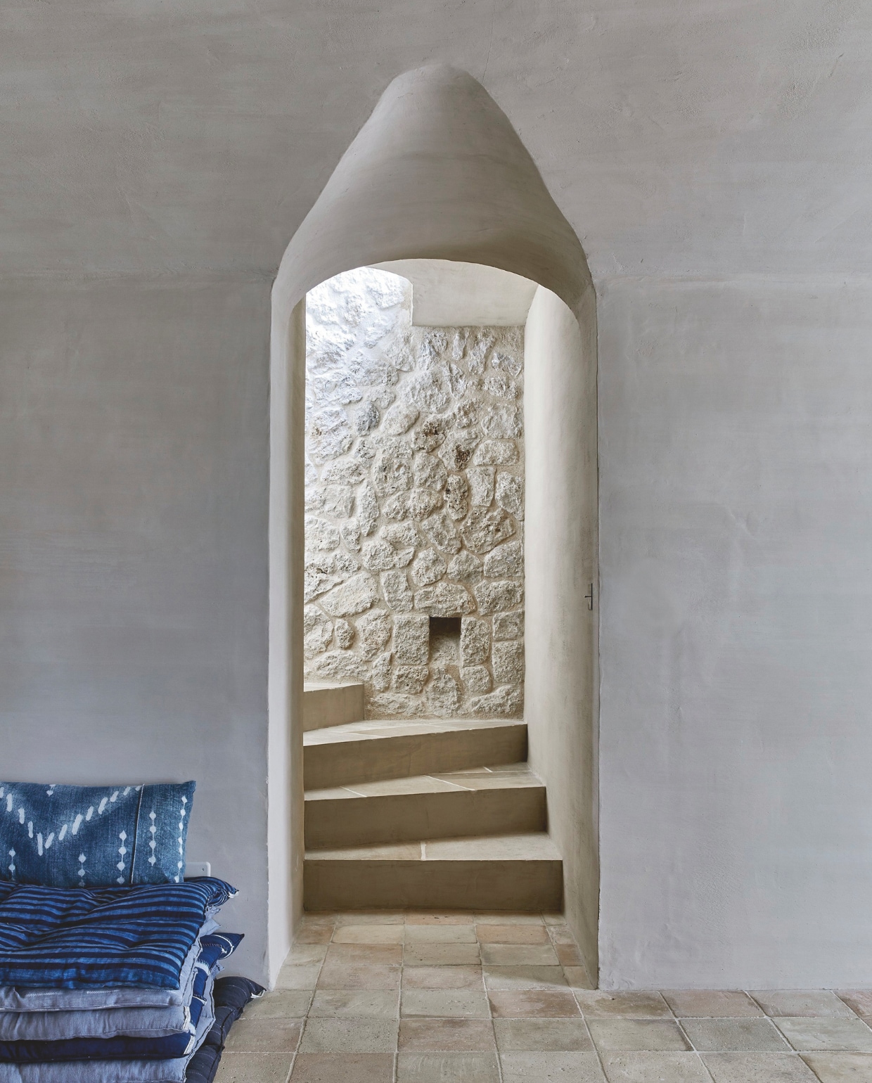 Het opvallende puntige boogdetail in traditionele Mallorcaanse stijl werd toegevoegd tijdens de renovatie. De trap verbindt een informele tv-lounge en extra slaapkamers met de open leefruimtes erboven. Stijlvol Wonen 04-2025 | fotografie Greg Cox | tekstbewerking Anneleen Peeters | productie Sven Alberding/Bureaux/Living Inside | brontekst Robyn ALexander