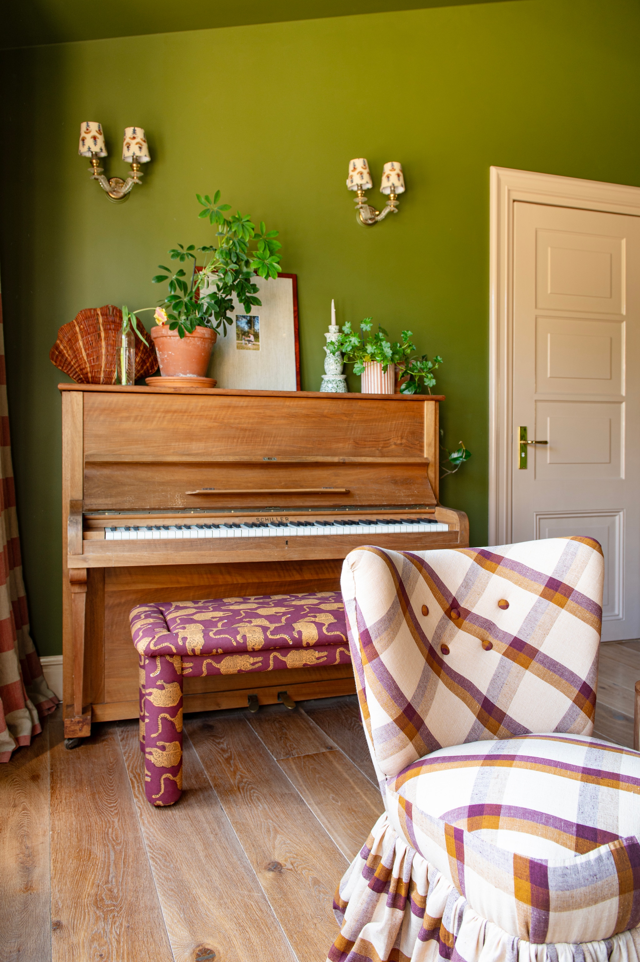 Muurkleur Bancha van Farrow & Ball. Piano gratis opgehaald via Marktplaats. Gordijnen gemaakt met linnen stof van Bemz, wandlampen gevonden op antiekmarkt, kapjes van CheLuz. Pianokruk zelfgemaakt en bekleed met blockprint plaid van Doing Goods. Rieten schelp kringloop. Lijst met passe-partout via Passe-partout shop. vtwonen DIY special 03-2025 | fotografie Caroline Coehorst