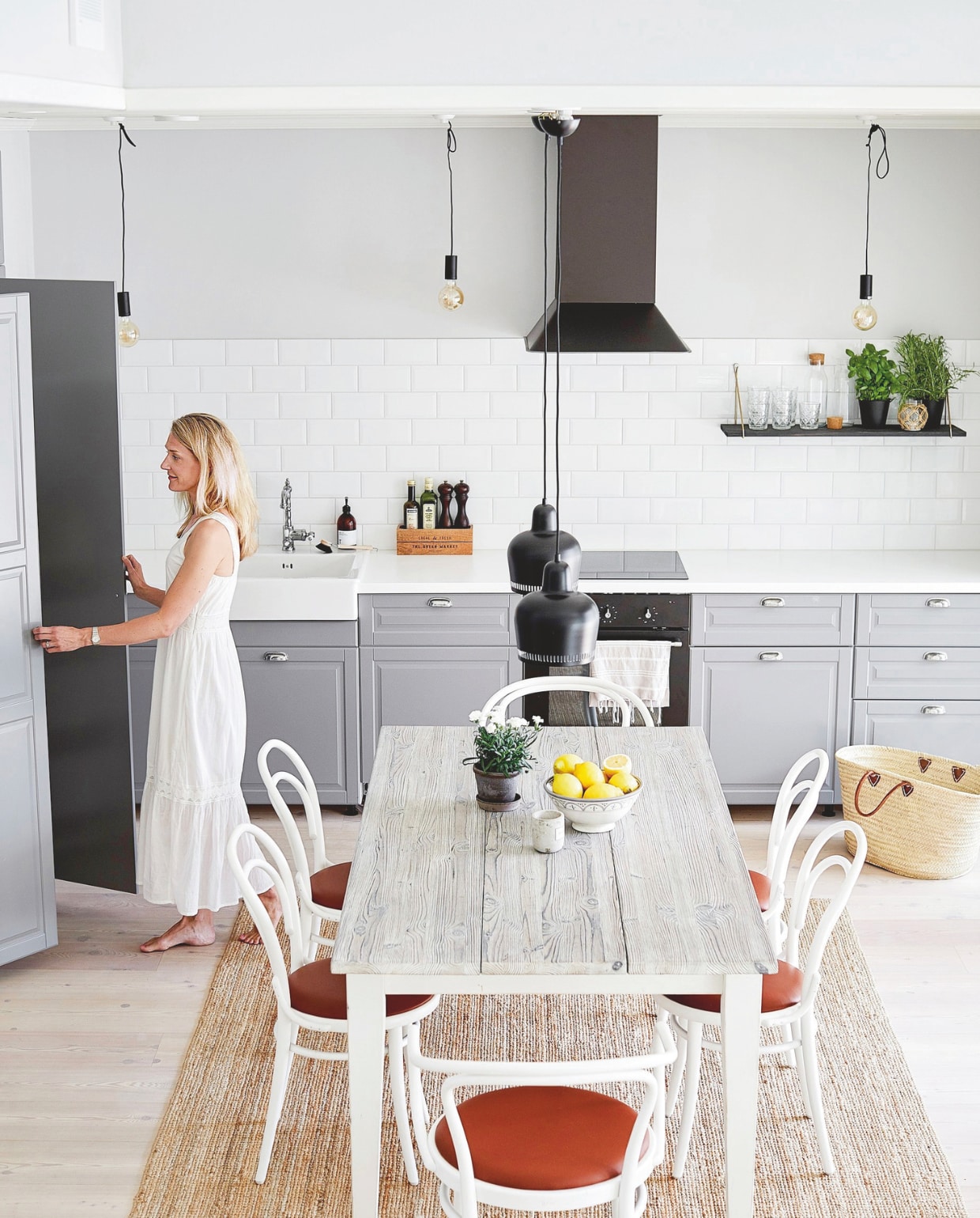 Keuken Bodbyn van Ikea, met een porseleinen wasbak, laminaat werkblad en metalen komgrepen. Tafel gemaakt van oud hout. Stoelen 214 P van Thonet. vtwonen Landelijk 05-2024 | styling Jonna Kivilahti | fotografie Krista Keltanen