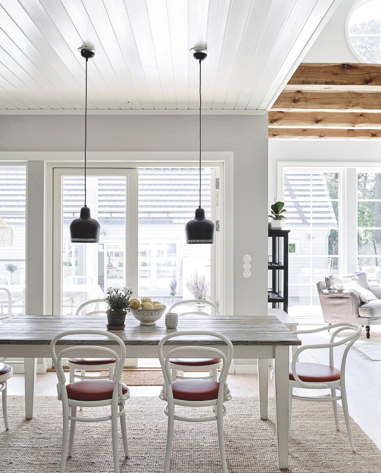Eettafel op maat gemaakt van oud hout. Stoelen 214 P van Thonet, met leren bekleding. Hanglampen Artek. vtwonen Landelijk 05-2024 | Styling Jonna Kivilahti | Fotografie Krista Keltanen