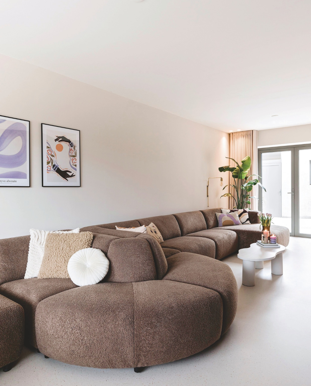 Bank Aardeko. Kussens Sissy-Boy, Westwing en H&amp;M Home. Salontafel zelfgemaakt door Sjors. Posters Desenio. Gordijnen Eef Wonen. Kleur wand Frosted Sand van Lab Paint. vtwonen 05-2025 | fotografie Corine Hoge Bavel
