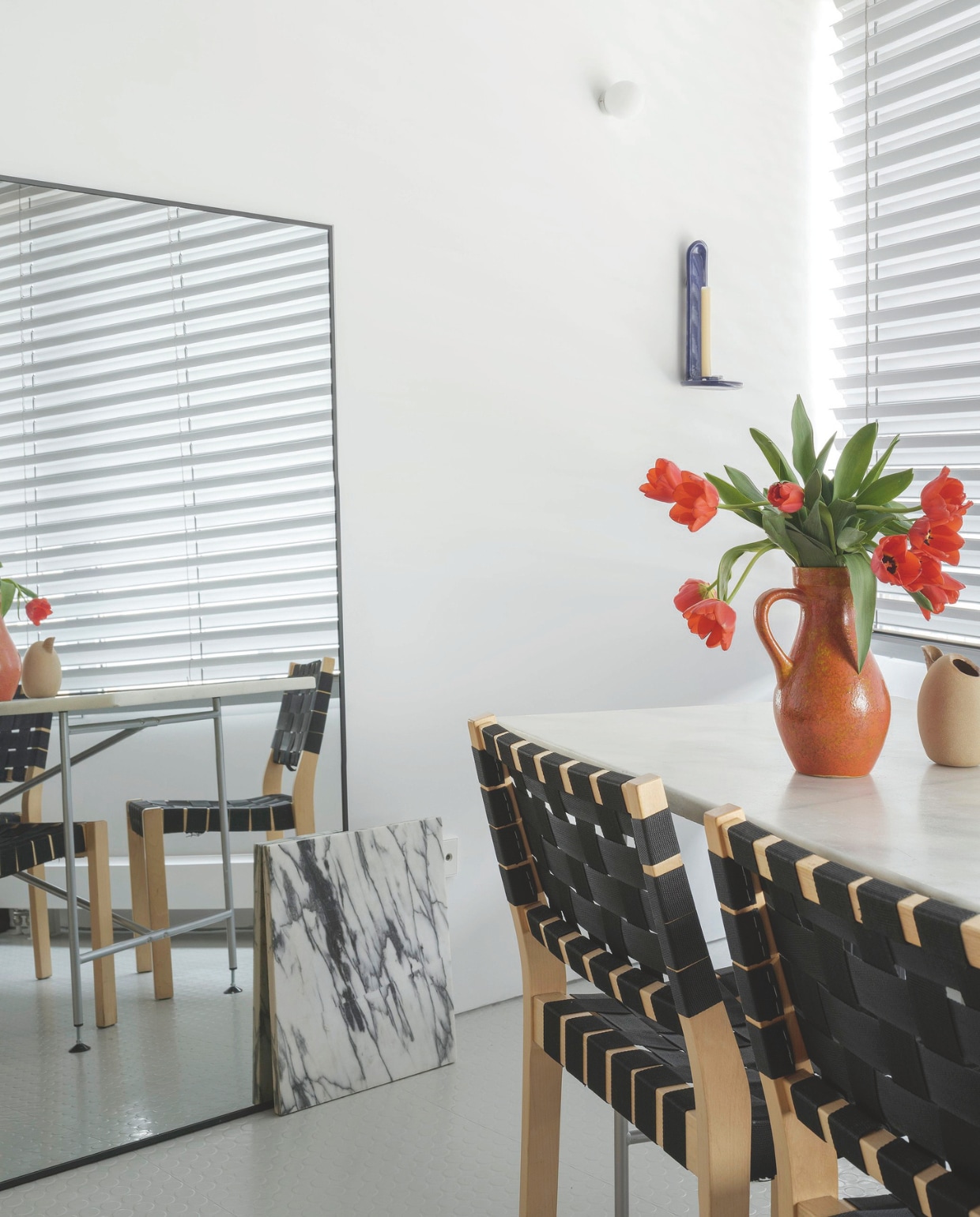 Eetkamerstoelen van Alvar Aalto voor Artek aan een vintage tafel. Blauwe kaarsenhouder van Spaanse keramiekstudio Ofenhaus. Een rest marmer dient als decoratief element. Stijlvol Wonen 05-2025 | fotografie Luis Díaz Díaz | tekst Jackie Oomen