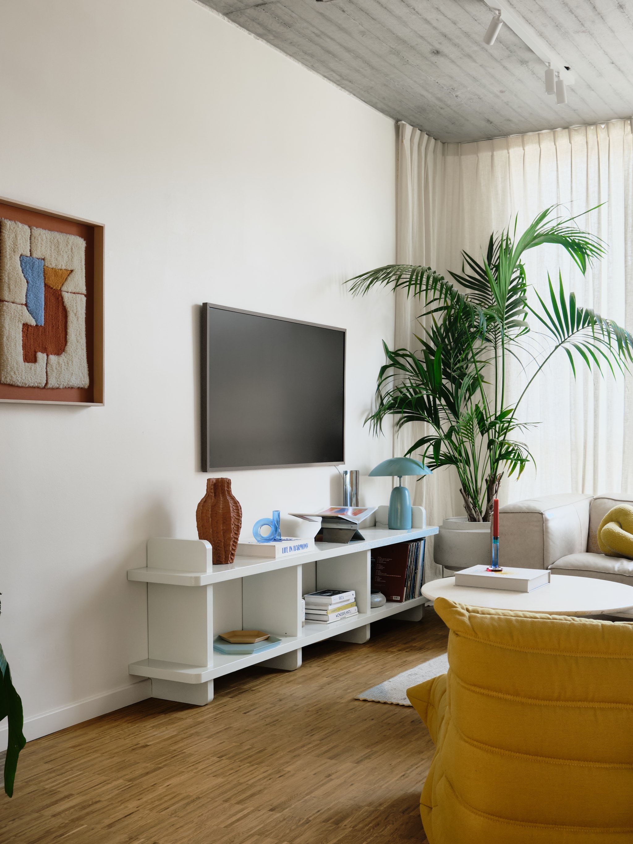 Kunstwerk gemaakt door Camille. Dressoir eigen ontwerp, op maat laten maken door een timmerman. Vintage travertijnen salontafel Roche Bobois. Fauteuil Togo van Ligne Roset. Bank Dunbar van Fést. Bijzettafel DLM van Hay. Hangkast Bond van Fogia. Oranje fauteuil Skalboda van Ikea. Tv The Frame van Samsung. Verlichtingrail op maat gemaakt door Cone Lighting. stijlvol wonen 7-2025 | fotografie Mr. Frank