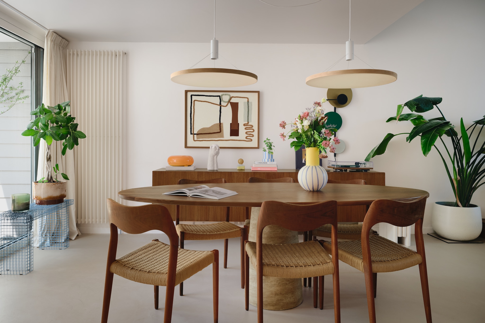 Stoelen Model 71 van Niels Otto Møller. Tafel en witte beeld van winkels die niet meer bestaan. Dressoir Dieter Waeckerlin. Wire Bench van Kalager Design. Verlichting Floating light van Thijmen van der Steen. Kunstwerk Lrnce. Oranje tafel/muurlamp Varmblixt van Ikea. Vaas Motel a Miio. Potje met geel deksel Zara home. Wandlamp Planet van Please wait to be seated. stijlvol wonen 7-2025 | fotografie Mr. Frank