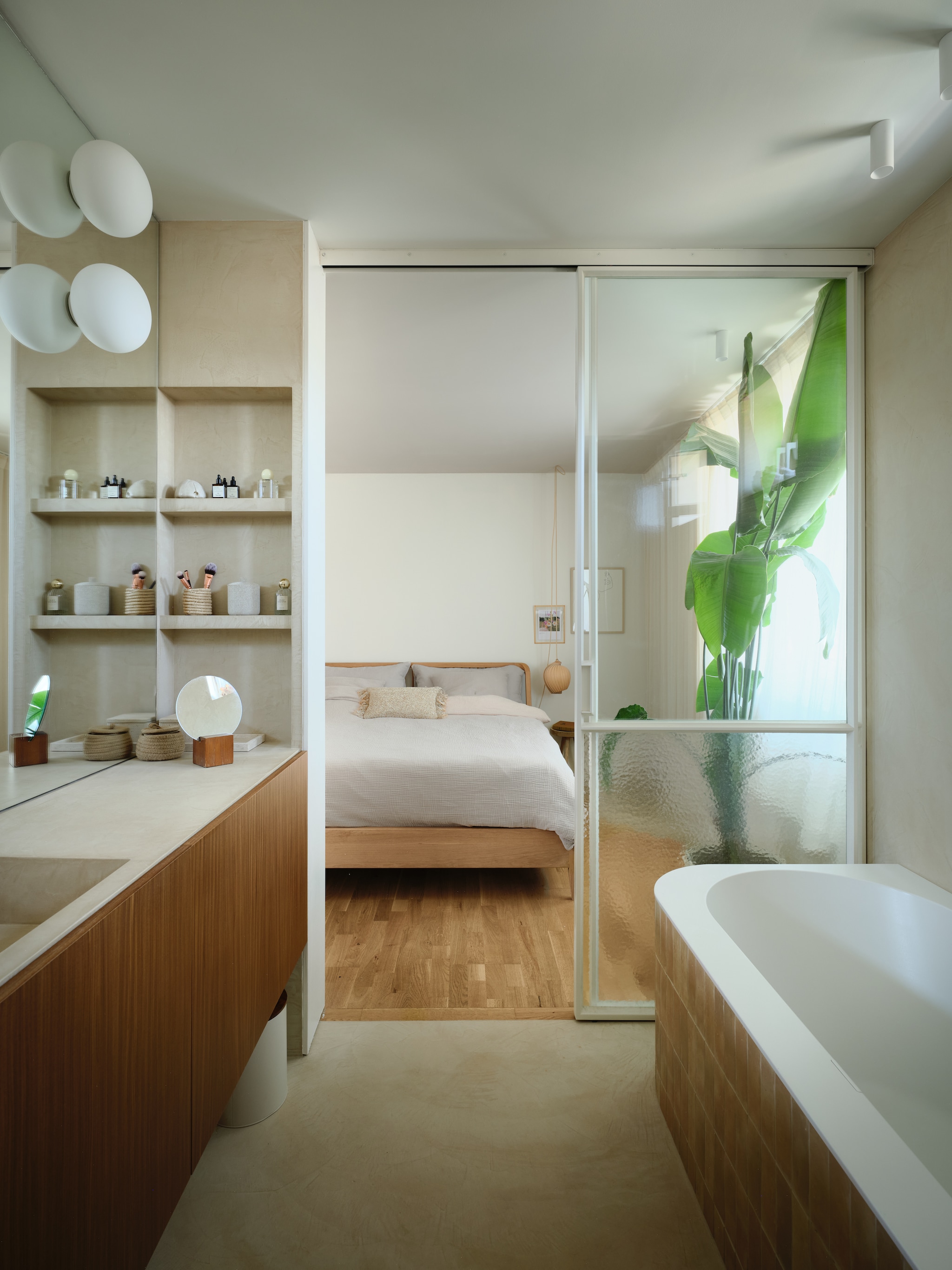 Door de muur tussen slaapkamer en badkamer open te breken, ontstond er een ensuite badkamer, die zorgt voor een ruimte- én luxegevoel. De badkamer kreeg een zandkleurige stuclaag van microcement. Rond het bad kwamen er terracottakleurige tegels, een verwijzing naar de wand in de entree. stijlvol wonen 7-2025 | fotografie Mr. Frank
