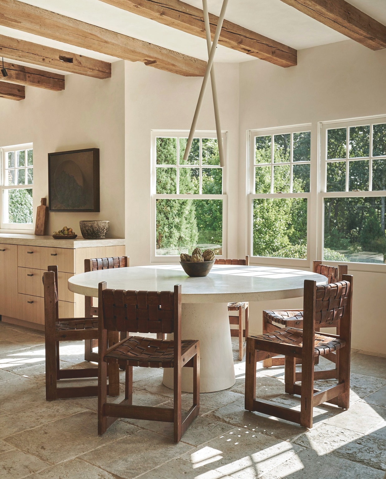 Op de vloer 400 jaar oude Franse dallen uit een Franse boerderij. Op maat gemaakte eettafel van keramiek en beton door Studio Loho. Stoelen met leren zittingen Scandinavisch design uit 1940. Plafondlampen van klei van Carlyle Collective. Kunstwerk Leonard Woodruff. vtwonen Landelijk 05-2025 | styling Colin King | fotografie Adrian Gaut  | tekstbewerking Margreet van Schaik