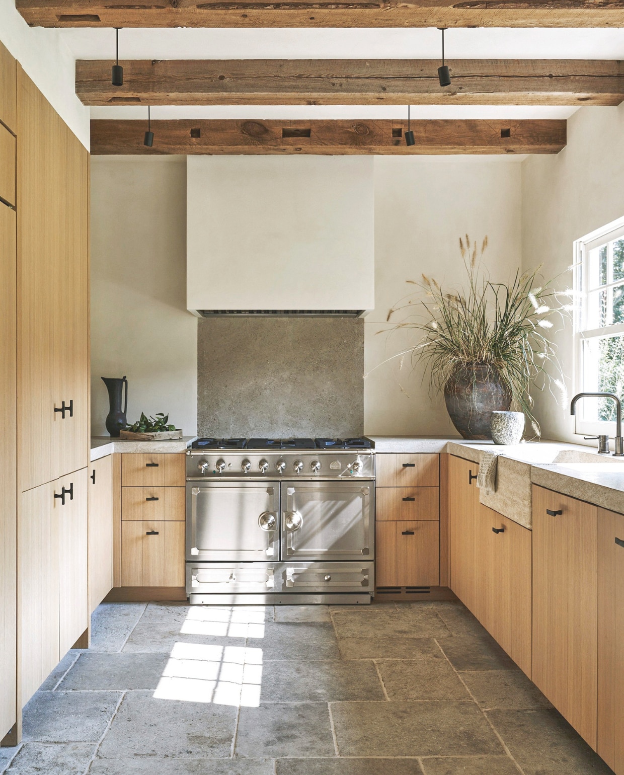 Maatwerk keuken van wit eikenhout van Copperwood Specialties. Bronzen knoppen Lerou. Fornuis La Cornue. Kraan Dornbracht. Waterkan Silvia Valentín. Kruik antiek. vtwonen Landelijk 05-2025 | styling Colin King | fotografie Adrian Gaut  | tekstbewerking Margreet van Schaik