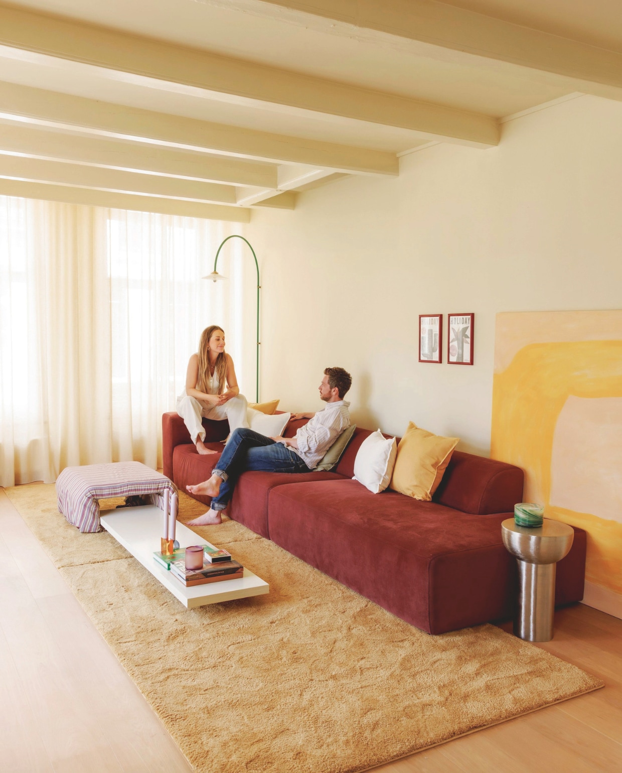 Muur en plafond in Asian Sunrise van Lab Paint. Gordijnen Nuzzle in Lemon Meringue van Vadain. Bank X6 van 4X6 Sofa in Wine Red. Poef en salontafel zelfgemaakt. Wandlamp Muller Van Severen voor Valerie Objects via Mud in May. Linnen kussens H&amp;M Home. Twee dezelfde vloerkleden tegen elkaar van Karwei. Waxinelichthouder HKliving. Kandelaars Fest. vtwonen 06-2025 | styling Kelly Van Gendt | fotografie Emma Peijnenburg