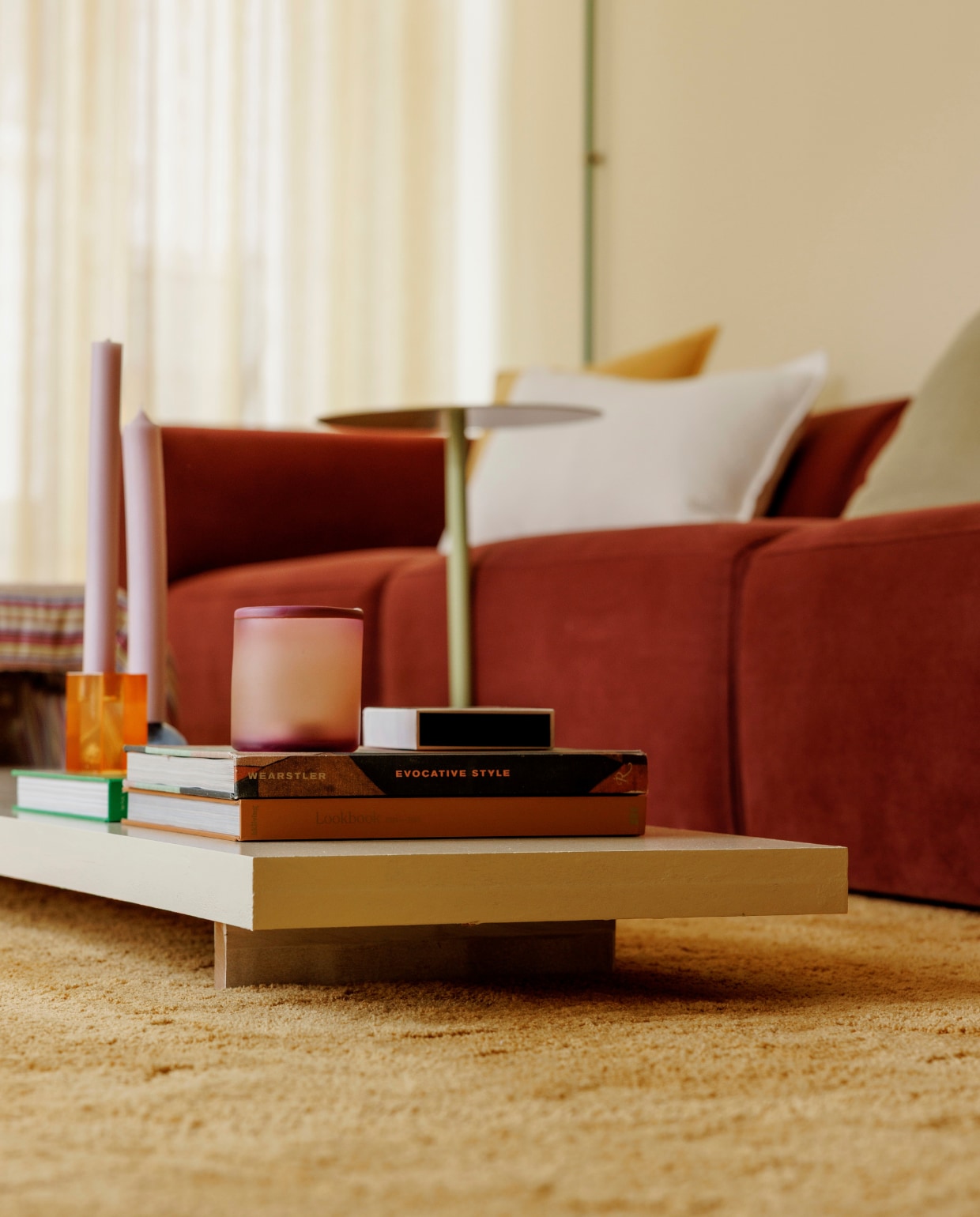 Muur en plafond in Asian Sunrise van Lab Paint. Gordijnen Nuzzle in Lemon Meringue van Vadain. Bank X6 van 4X6 Sofa in Wine Red. Poef en salontafel zelfgemaakt. Linnen kussens H&amp;M Home. Twee dezelfde vloerkleden tegen elkaar van Karwei. Waxinelichthouder HKliving. Kandelaars Fest. vtwonen 06-2025 | styling Kelly Van Gendt | fotografie Emma Peijnenburg