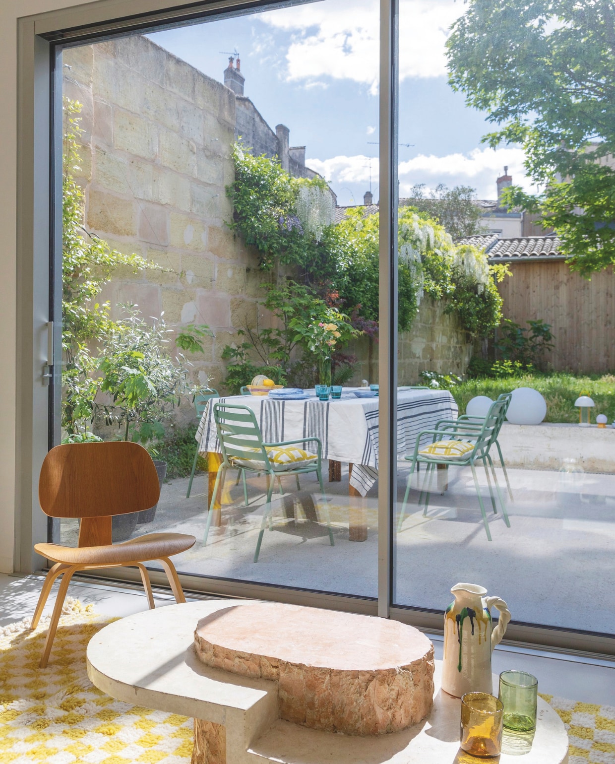 Vloerkleed BerberChico van Obi Home, stoel Eames Lcw van Vitra, salontafel Maitland-Smith, tuinstoelen en tuintafel Casa, tafelkleed Maison Jean-Vier, buiten-lampen Hay en Ikea, waterglazen Iittala. vtwonen 06-2025 | productie AC Scoffoni | styling Marie-Maud Levron | fotografie Cécile Perrinet Lhermitte