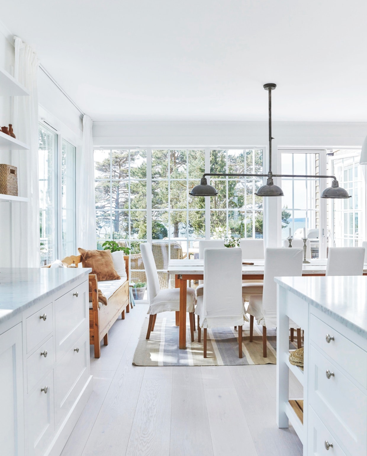 Keuken Kvänum, met blad van marmer. Eettafel zelfgemaakt van oude poten en witgeoliede houten plank. Stoelen Artwood. Hanglamp beurs inParijs. Houten bank van Kristina’s moeder.Tafellaken Lexington. vtwonen Landelijk 05-2025 | Fotografie Birgitta Wolfgang Bjørnvad | Tekstbewerking Britte Kramer