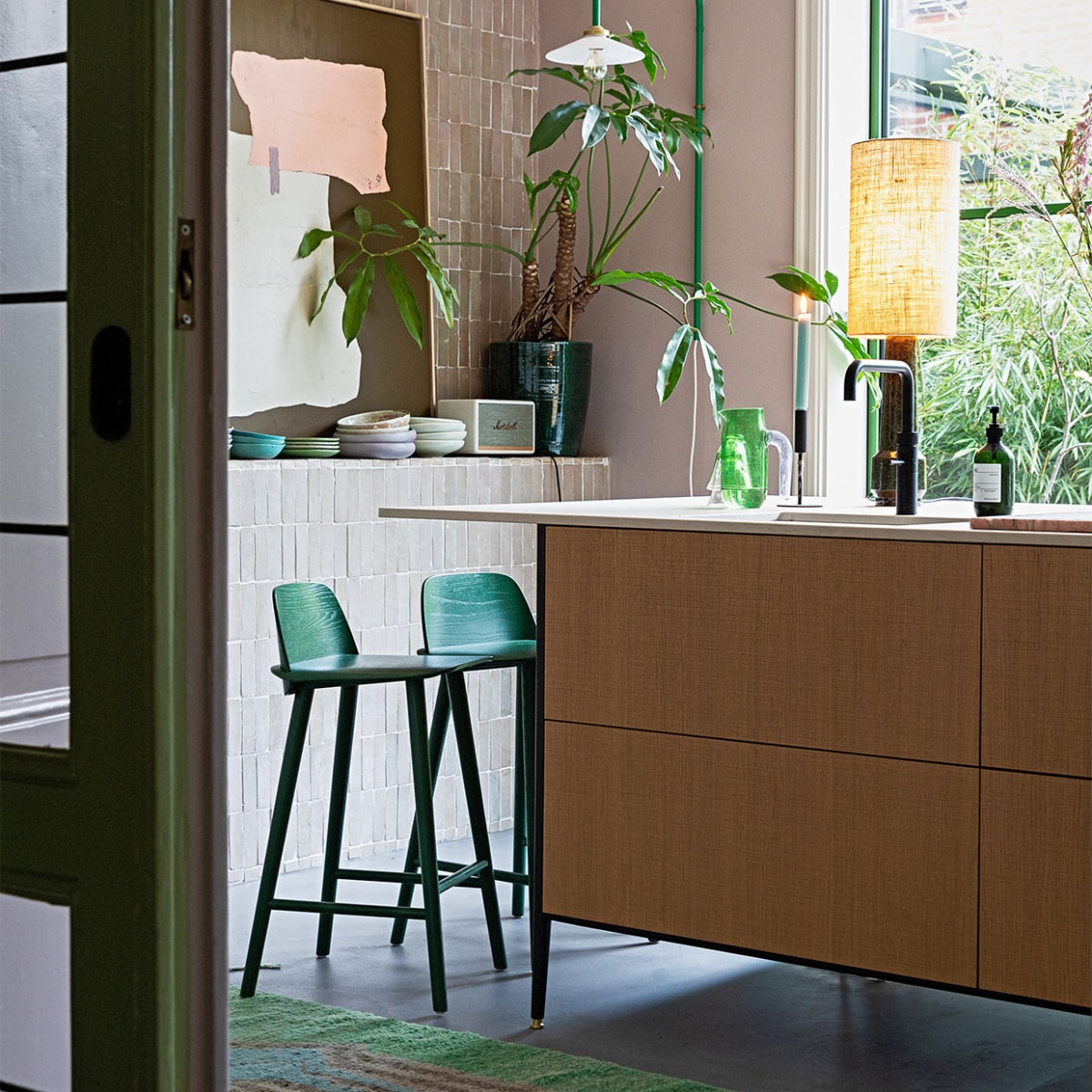 Groene lamp aan muur Valerie Objects. Tegels Bejmat Gris rose Marokkaanse tegels via Design Tegels. Schemerlamp en kunst HKliving. Kandelaar Hema. Kan Hay. Plantenpot Serax. Muziekbox Marshall. Servies mix van onder andere Home Chef en 70’s ceramics van HKliving. Krukken Nerd van Muuto. Keuken Unit van Cesar Kitchens. Kleed vintage berber. Aluminium pui in kleur Varen Groen. Lamp plafond onbekend. vtwonen 05-2022 | styling Ilona Jongepier | fotografie Dana van Leeuwen