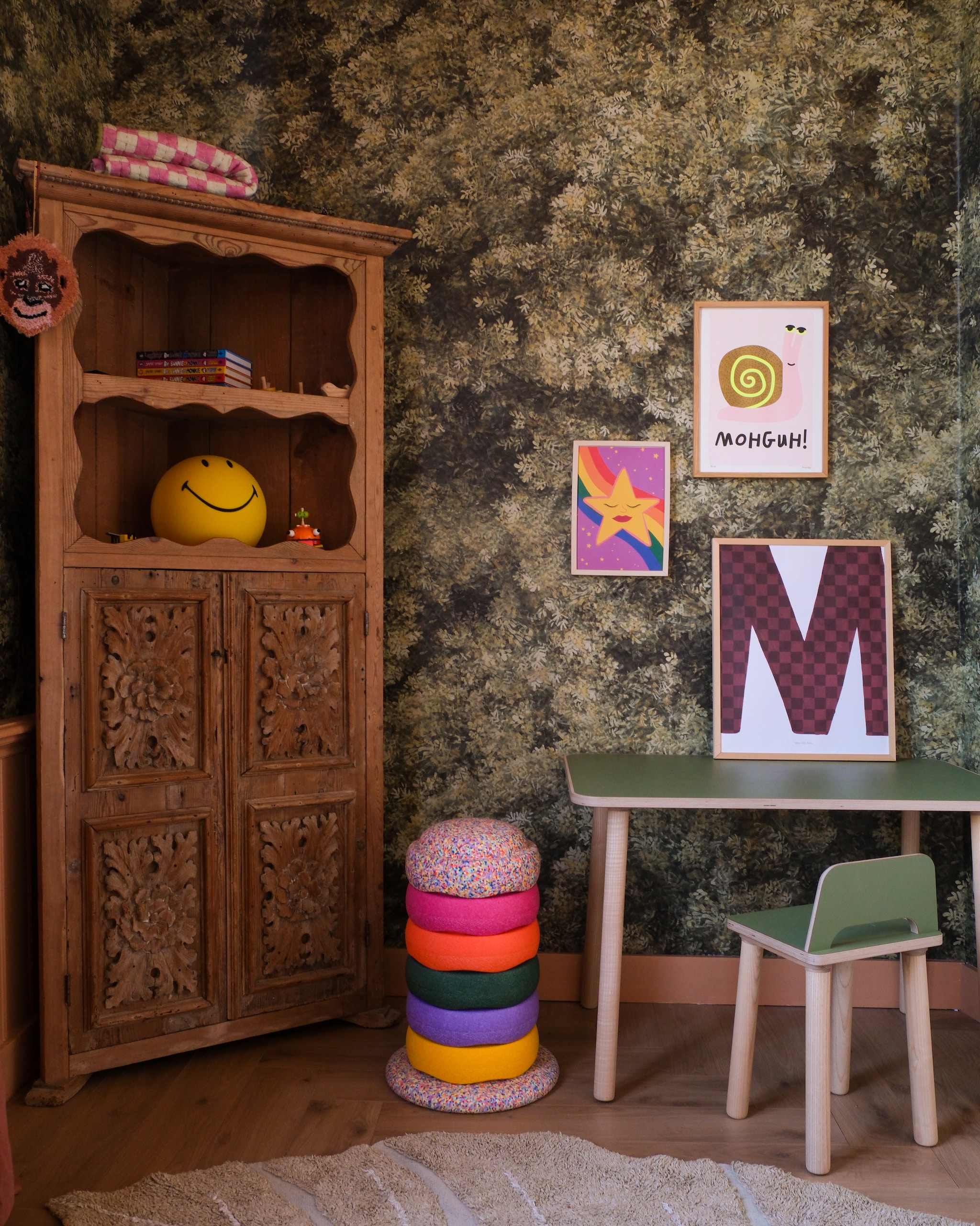De hoekkast is een erfstuk. Aaphanger Doing Goods, deken Unknown Stories, Smiley-lamp Mr Maria, stapelstenen Stapelstein. Tafel en stoel Ettomio. Poster met slak Agoe Agoe, letterposter Mr Starsky, poster met ster Jungle Mumble Design. Vloer laminaat visgraat Peterselie van Douwes Dekker, behang Wild Forest  van Belartestudio in Olive Green, plint geverfd met Orange Barista van Lab Paint. fotografie Rio van der Oest @mostlymosi