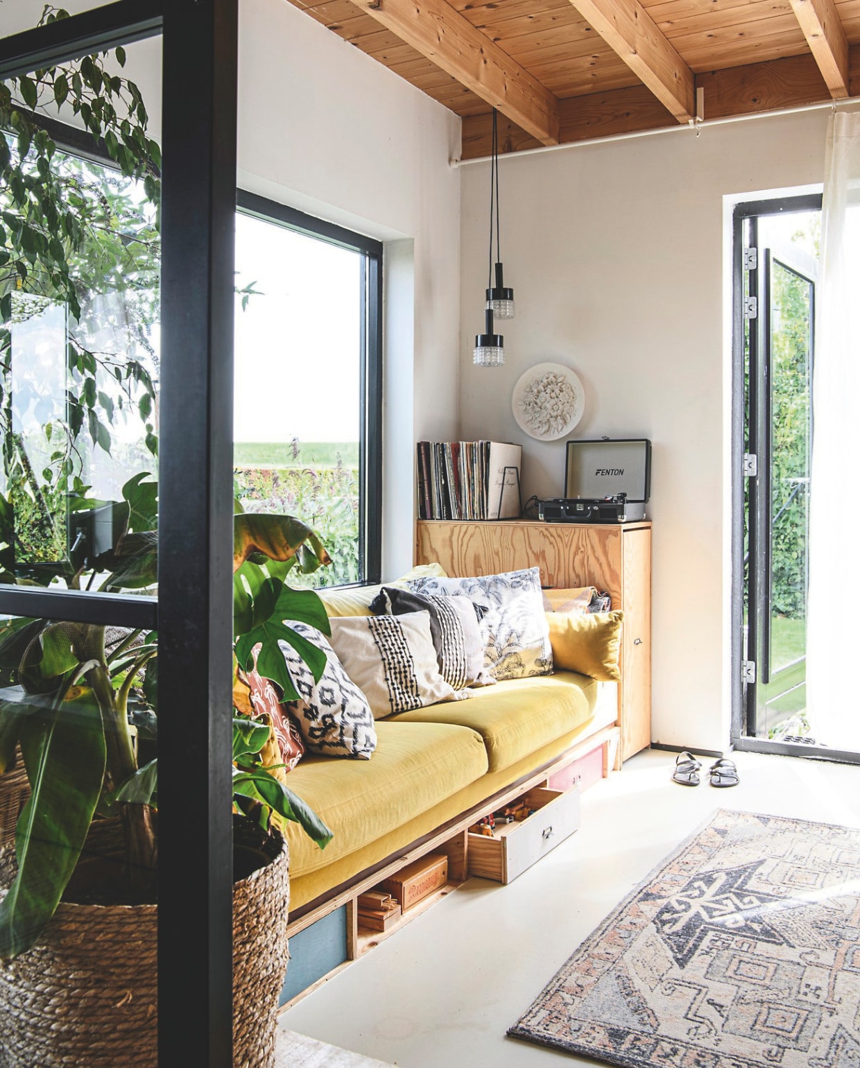 Plantenmand en koffer kringloop. Gietvloer Stamvloeren. Houten kasten zelfgemaakt, hanglampen Marktplaats. Vloerkleed en bank Nous Living. Kussens Wehkamp, H&M Home en Zara Home. vtwonen 06-2025 | styling Fiona Richardson | fotografie Lisa Cohen