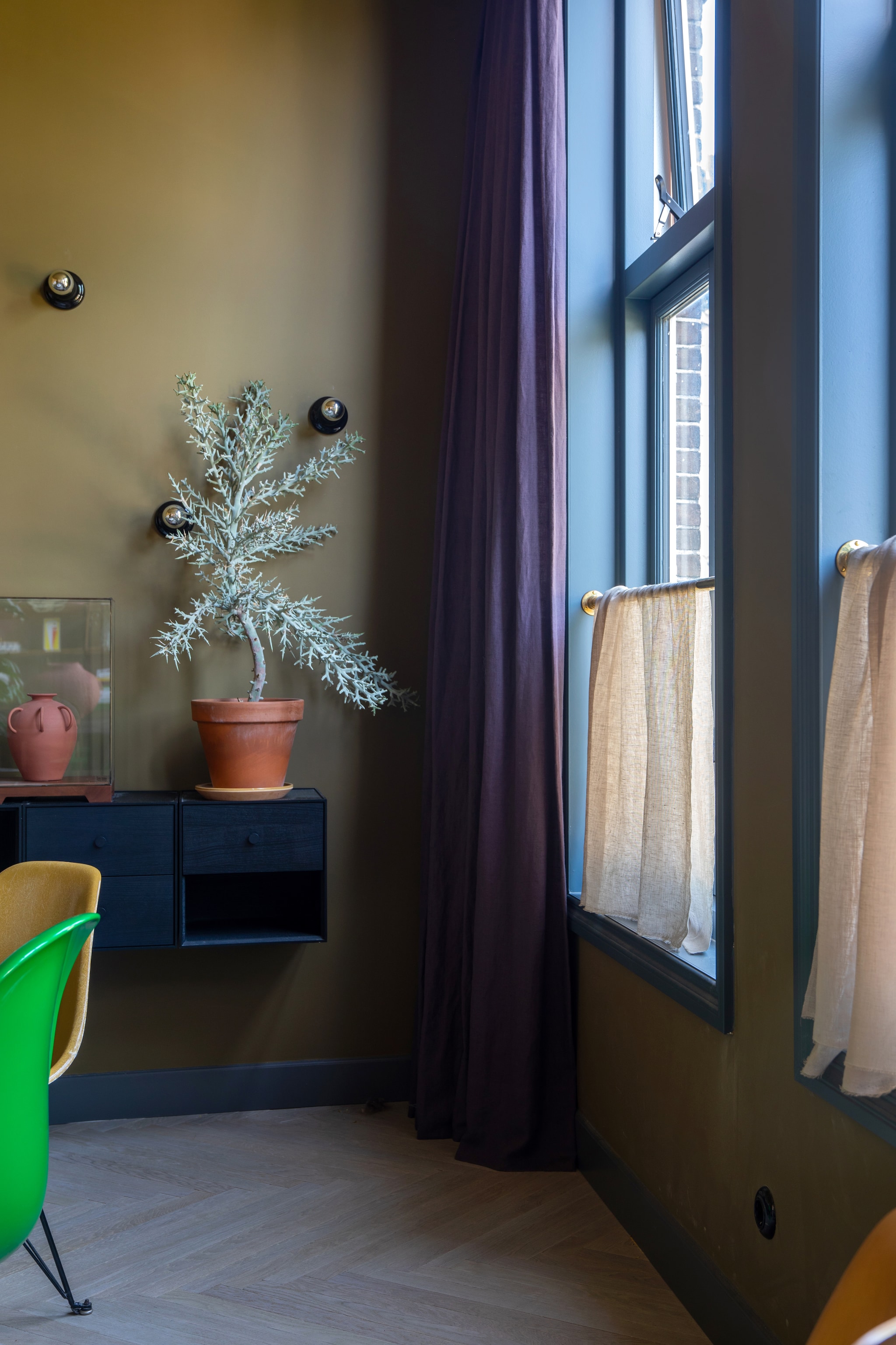 Kleur muren en plafond The Greenhouse 7 van Flexa, houten vloer Vloerenhuis Amsterdam. Eettafel Knoll, stoel links Carl Hansen Pink Limited via Mister Design, groene stoel Vitra. Kunstwerk links Werk aan de Muur, kunstwerk rechts gemaakt door Theo-Berts opa. Tafellamp op schouw Flos. Dressoir Audo, kaarsenhouder teckel Theo-Bert Pot by Karwei. vtwonen 09-2025 | styling & fotografie Theo-Bert Pot en Jelle Van de Schoor