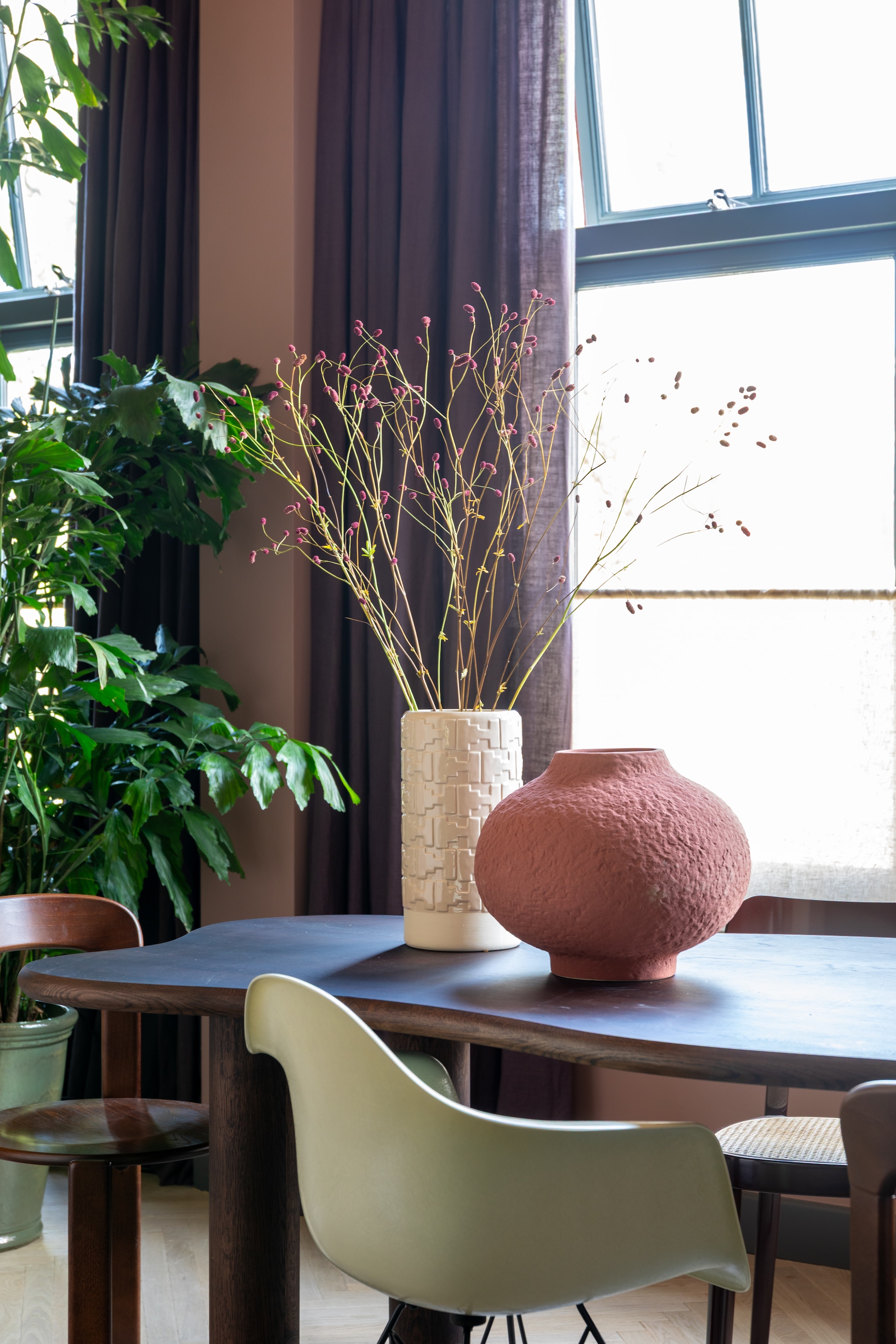 Kleur muur en plafond Nice Pink van The Nice Stuff Colours by Flexa x Karwei, kleur kozijnen Nice Night van The Nice Stuff Colours by Flexa x Karwei, houten vloer Vloerenhuis Amsterdam. Linnen gordijnen Evert Groot. Eettafel Table du Sud, stoel aan kopse kant Hay, witte stoel Vitra, vaas Theo-Bert Pot by Karwei, hanglamp Ay Illuminate. Kast String Furniture via Loft76, rode vaas Cor Unum via Drent & van Dijk, organische vaas HKliving. Auberginekleurige lamp &Tradition via Flow Lab Rotterdam, vaas rechts onderin kast Merci Parijs, tafellamp ernaast Gubi. vtwonen 09-2025 | styling & fotografie Theo-Bert Pot en Jelle Van de Schoor