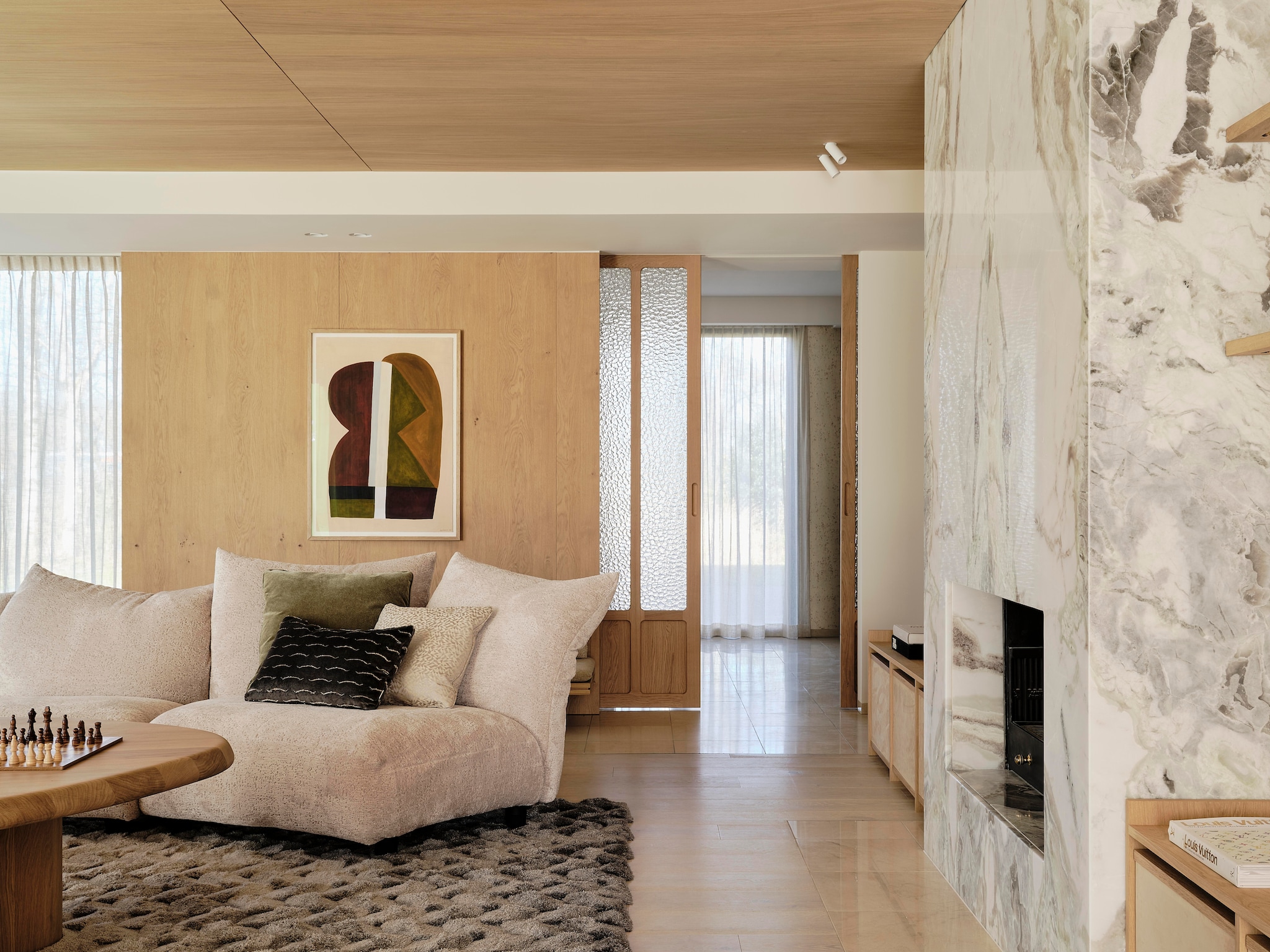 Modulaire bank Edra. Kussens gemaakt door Stoffeershop en bekleed met stof van Dedar en Zimmer + Rohde. Kleed Ferreira de Sá. Tafel Behout. Vazen Serax. Items planken links Maravillas, items planken rechts Roomer Art, Serax, HKliving. Tafellamp Oluce Atollo. Schouw Dover wit marmer. Zeegras behang Kudzu van Arte. stijlvol wonen 7-2025 | fotografie Space Content Studio