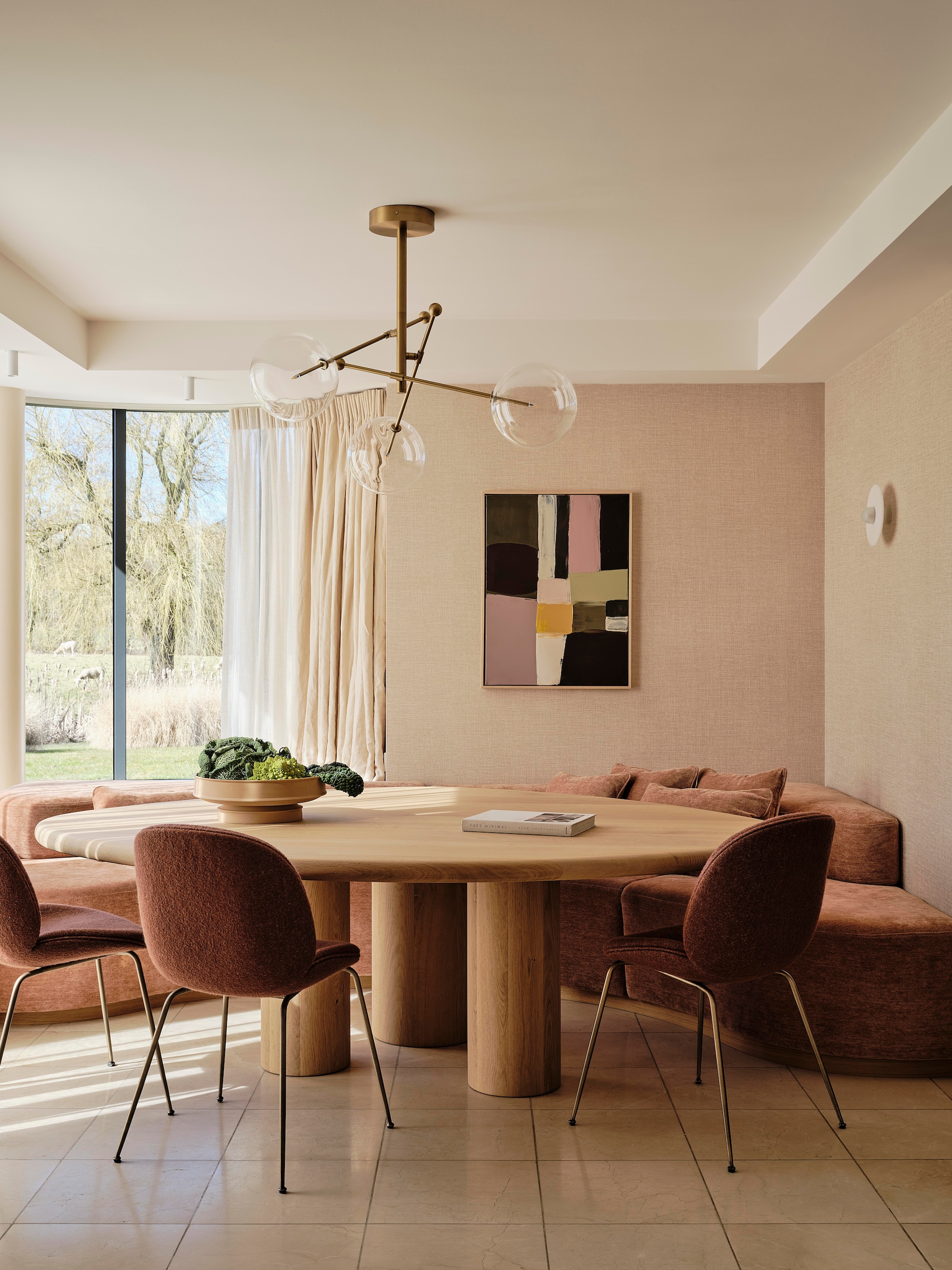 Bank ontworpen door Fleur Westerweel, gemaakt door ’t Kroonhuys en bekleed door Stoffeershop met stof Belsuede 032 van Dedar. Eettafel ontworpen door Fleur en gemaakt door Behout. Stoelen Gubi, bekleed met stof Harp. Schaal Serax. Hanglamp Schwung. Kunstwerk Roomer Art. Behang Raffia van Élitis. Wandlamp Alabaster van Contain. stijlvol wonen 7-2025 | fotografie Space Content Studio
