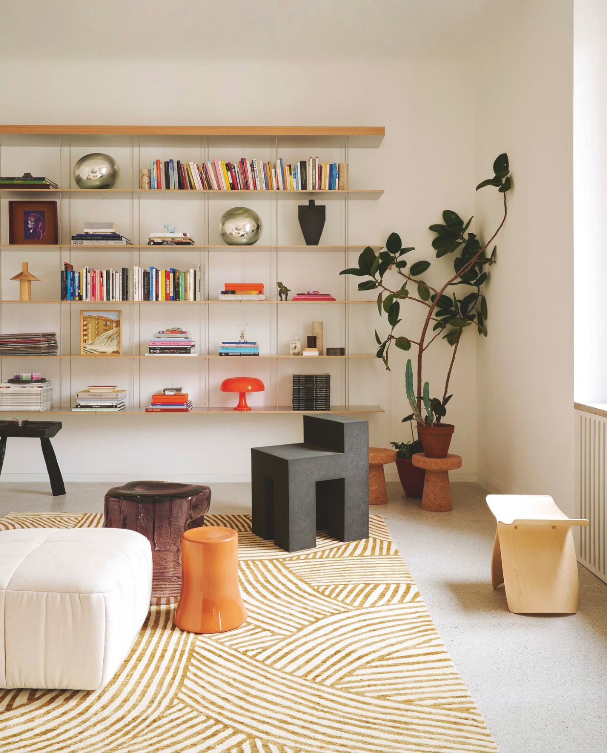 Boekenkast van Jean Nouvel voor Molteni. Vloerkleed Bethan Gray voor CC Tapis. Krukken Antonio Manara, Sori Yanagi en Jasper Morrison. Zwarte stoel Please Hold Up van Finemateria. Stijlvol Wonen 06-2025 | fotografie Valentina Sommariva