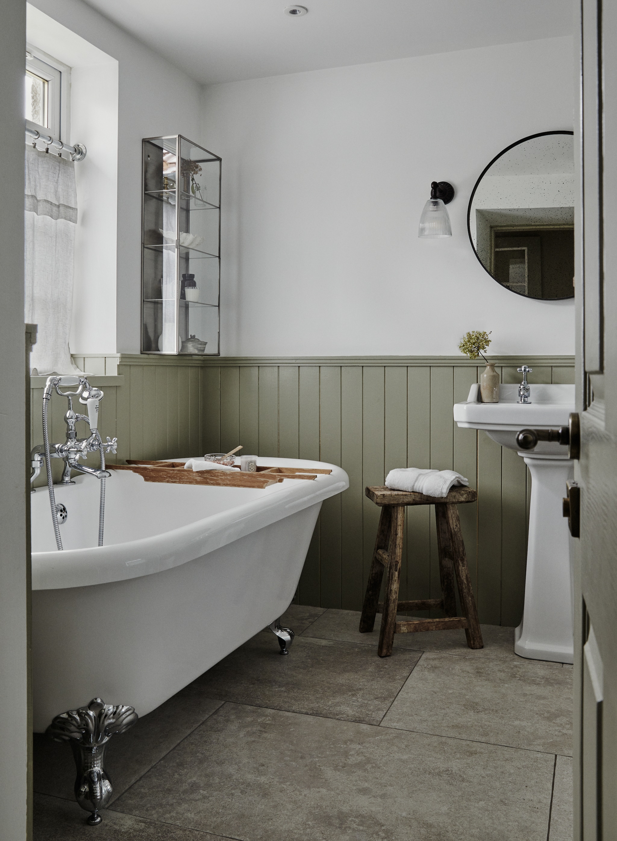 Houten lambrisering in kleur French Grey van Farrow & Ball. Stenen vloer via Ca’Pietra. Vergelijkbaar bad op pootjes en wastafel Hudson Reed en Windsor Bathrooms. vtwonen Landelijk 9-2025 | productie Living Inside | styling Ali Heath | fotografie Brent Darby