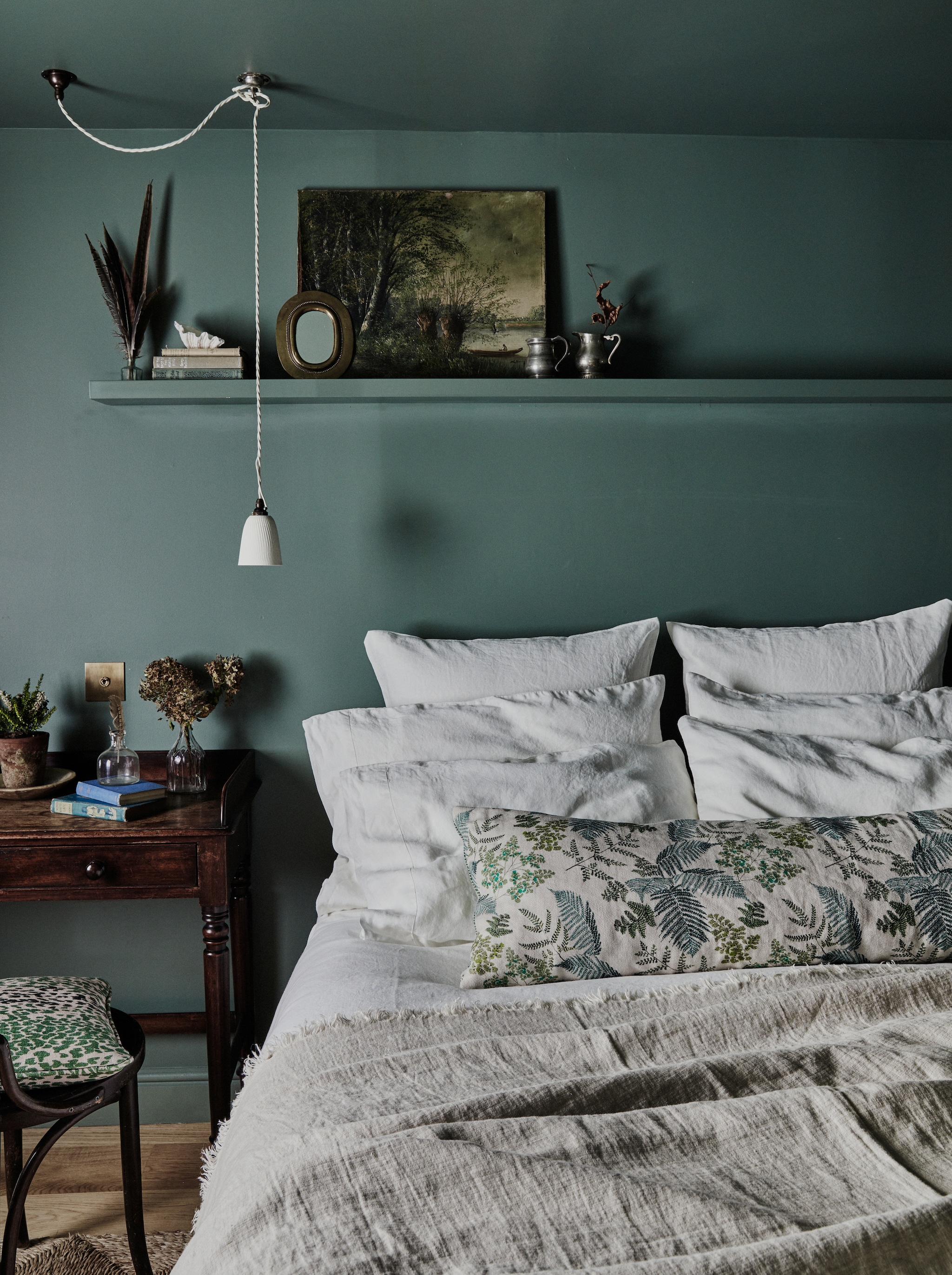 Kap-/schrijftafel, spiegel en stoel antiek. Vergelijkbaar vloerkleed Dalua van Boho Bali bij MyFaktory.>De slaapkamer met kleur Green Smoke van Farrow & Ball op de muur. Lamp deVol. Beddengoed Piglet in Bed. Stof kussen Parker & Jules. vtwonen Landelijk 9-2025 | productie Living Inside | styling Ali Heath | fotografie Brent Darby