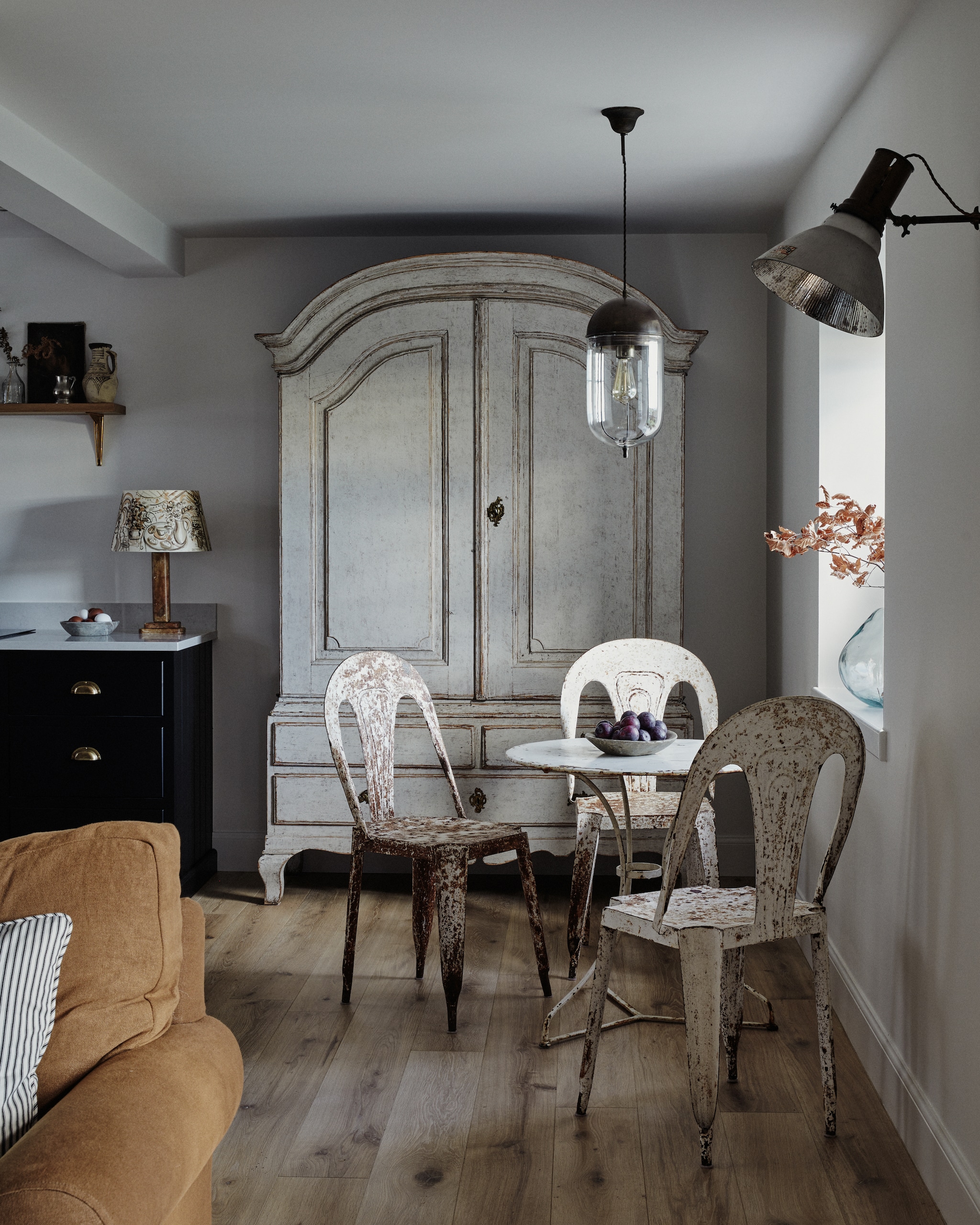 Links de handgeschilderde keuken van deVol, met natuurstenen blad en messing details. Kast Georgia Lacey. Tafel Haus. Stoelen Puckhaber Antiques. Wandlamp Matthew Cox. Hanglamp Alex MacArthur Interiors. vtwonen Landelijk 9-2025 | productie Living Inside | styling Ali Heath | fotografie Brent Darby