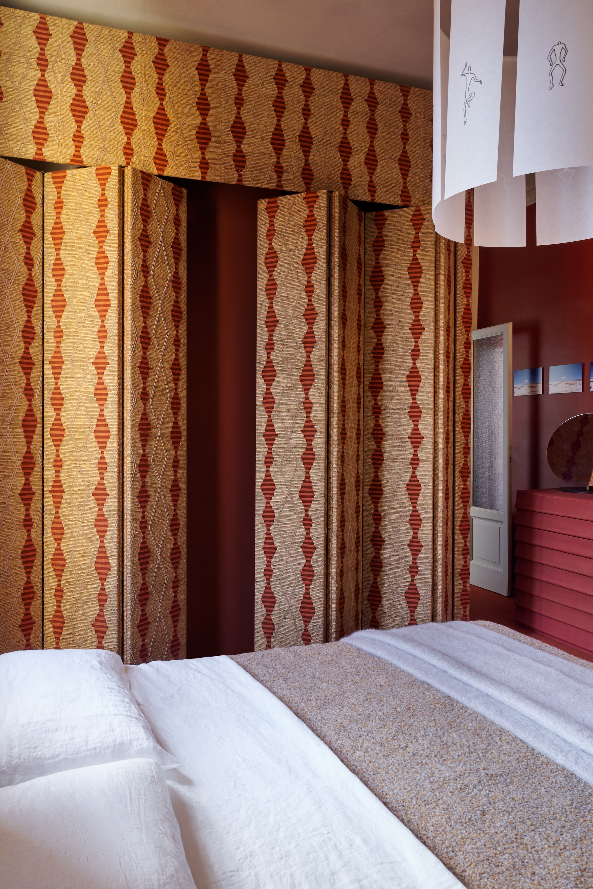 Vouwbare panelen Bolzan met bekleding van Fischbacher 1819. Bed Bend-e wood van Bolzan. Hanglamp Fog Drop van Andrea Branzi via Galleria Luisa Delle Piane. Beddengoed Lanerossi. Stijlvol Wonen 8-2025 | fotografie Valentina Sommariva, Irene Gaggia | productie Zanellato/Bortotto