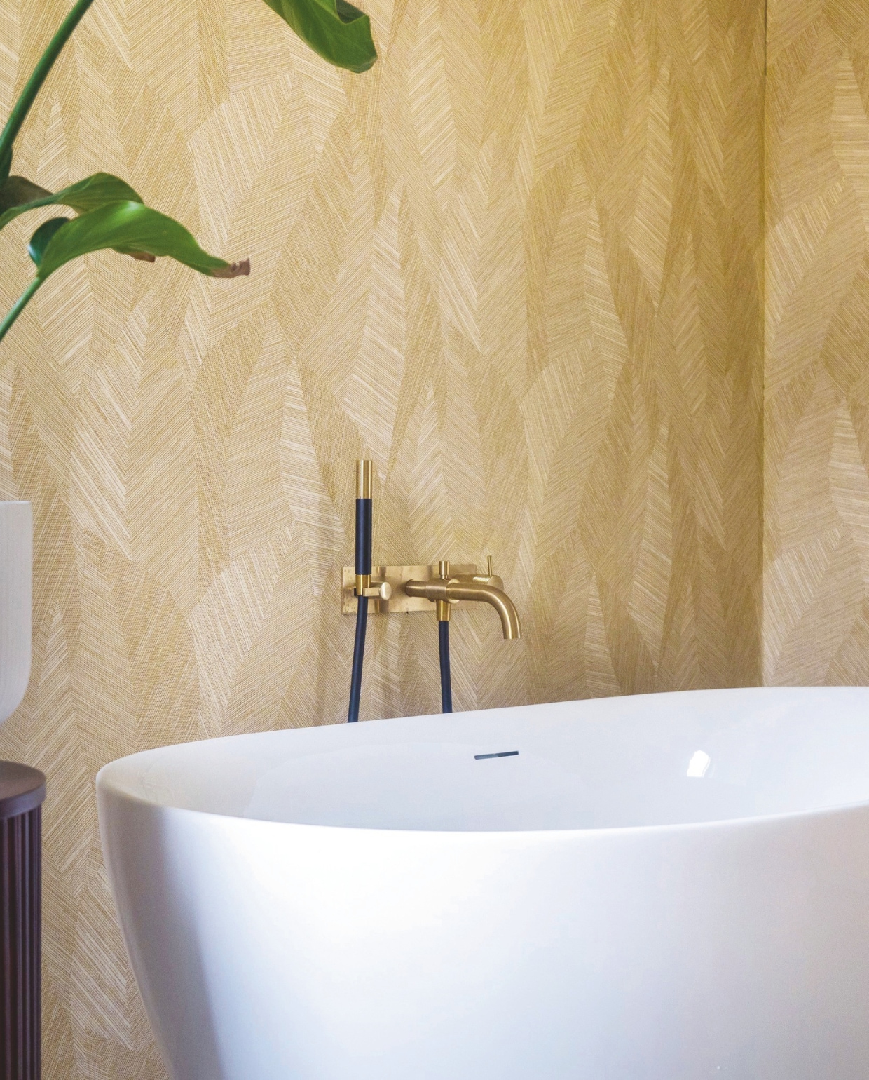 Behang in de badkamer? Dat kan zeker. Maak van de muur een eyecatcher. Zo past dessin Bounty uit de Essentials Tangram-collectie goed in badkamers met goudkleurige kranen. Facet uit de Monsoon-collectie laat juist koperen finishes stralen. (arte-international.com). Stijlvol wonen 05-2025 | dossier badkamers