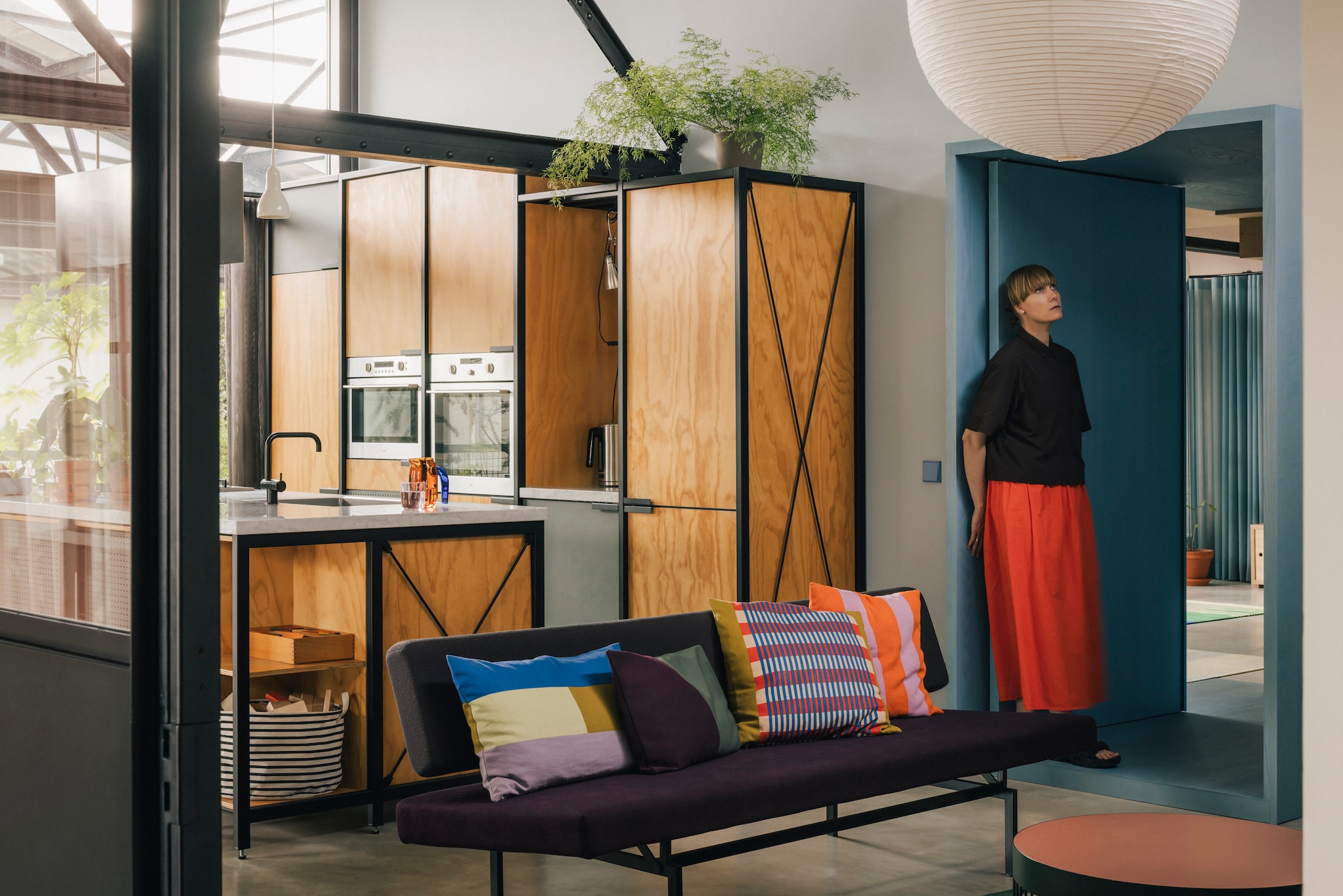 Keukenontwerp Studio Mieke Meijer. Bank BR53 door Martin Visser voor Spectrum. Glazen en kussens Tesammans eigen ontwerp voor Ikea. Oranje/roze kussen A world of Craft. Papieren hanglamp en waterkan Jug van Hay. Doorgang van essenhout in Helsinki van Linolie & Pigment. stijlvol wonen 8-2025 | fotografie Katoo Peeters
