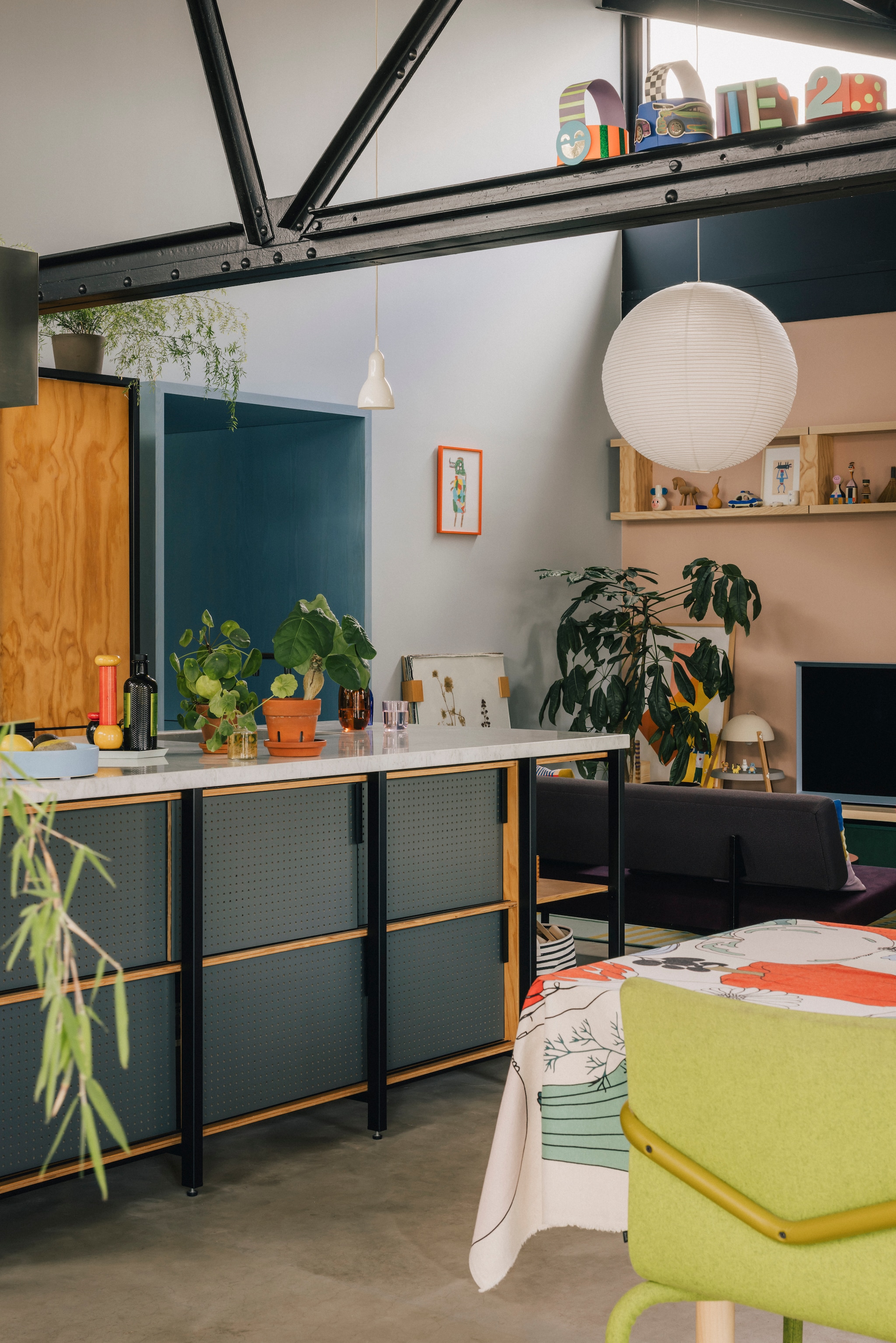 Muurverf S2.11.63 van Sikkens. Keuken ontworpen door Studio Mieke Meijer. Grote hanglamp Hay, kleine hanglamp Softlamp van Arian Brekveld, stalamp Daphna Laurens. Pepermolen Alessi. Eetkamerstoel Bertjan Pot van Arco. Tafelkleed Marimekko. Zelfgemaakte papieren feesthoedjes. Kunstwerk in oranje lijst gemaakt door zoon Ando. Kunstwerk tegen muur op de grond Herbarium van bevriende ontwerper Studio Maarten Kolk. stijlvol wonen 8-2025 | fotografie Katoo Peeters