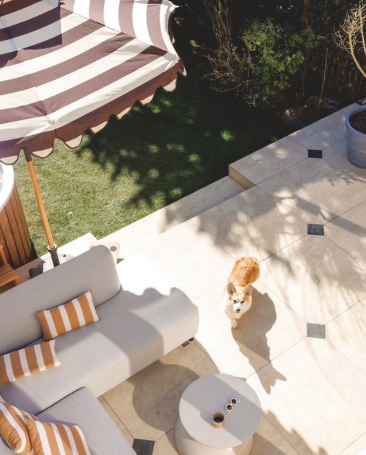 Tegels terras restpartij. Zwarte tegels Jan van IJken Oude Bouwmaterialen. Verwarmde buitenbank en gestreepte kussens Hartman. Salontafel Westwing. Poef Amstelièr. Plantenpot Elho. Parasol HKliving. Hottub Welvaere. vtwonen 7-2025 | fotografie Emma Peijnenburg