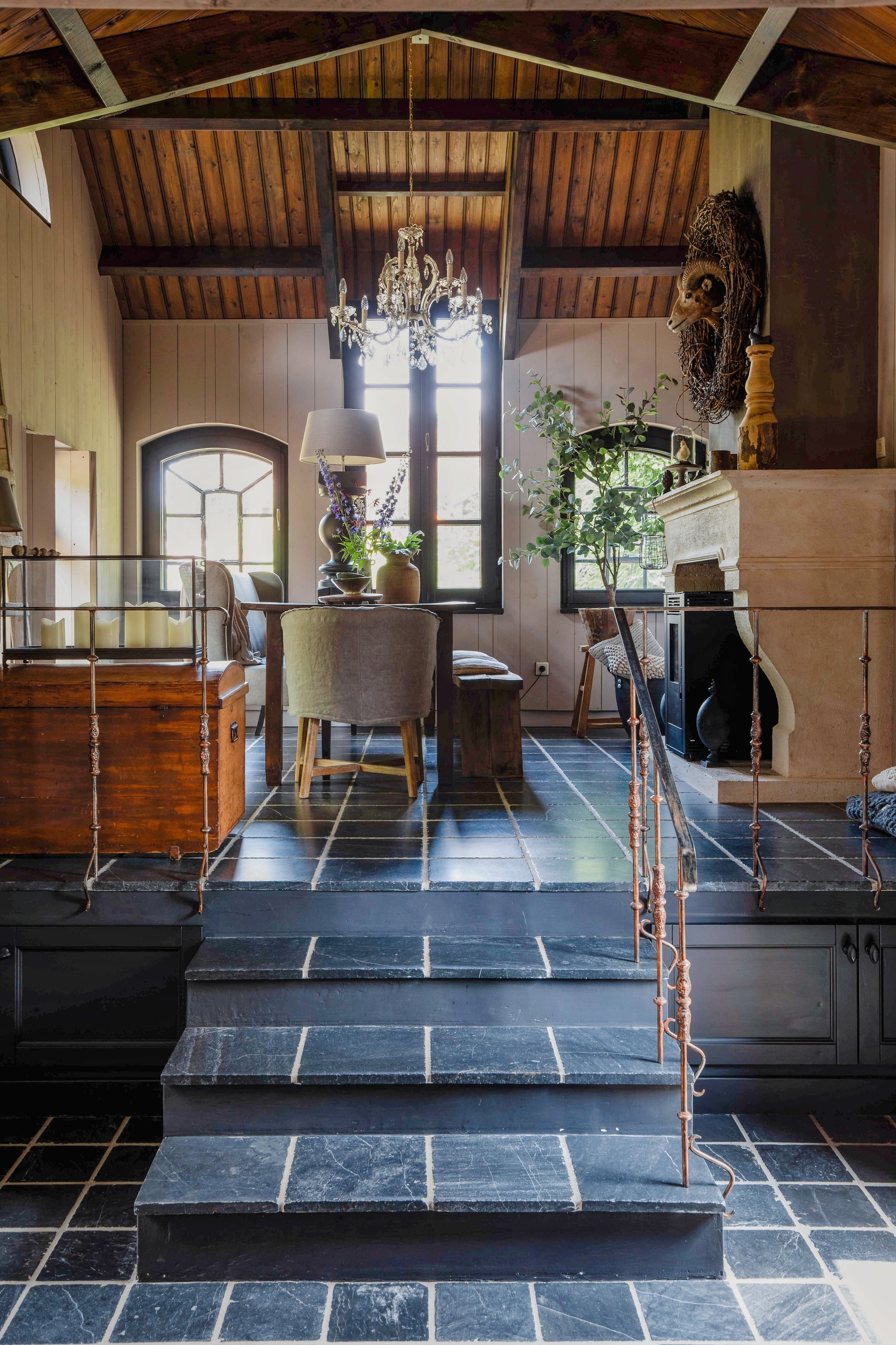 Het woongedeelte in aanbouw het ‘bakhuisje’. Voor de oorspronkelijke kozijnen zijn antieke, stalen stalramen gezet. Vloertegels via Marktplaats. Schouw gemaakt door de vader van Claudia. Dekenkist familiestuk. Kloostertafel antiek. Stoel Dirkje van Aura Peeperkorn via Bie ós. Houten bank Landelijk at Home. Lamp op tafel door Jack gemaakt van een balluster van ’t Potterieke. vtwonen Landelijk 9-2025 | Fotografie Corine Hoge Bavel-Jansen