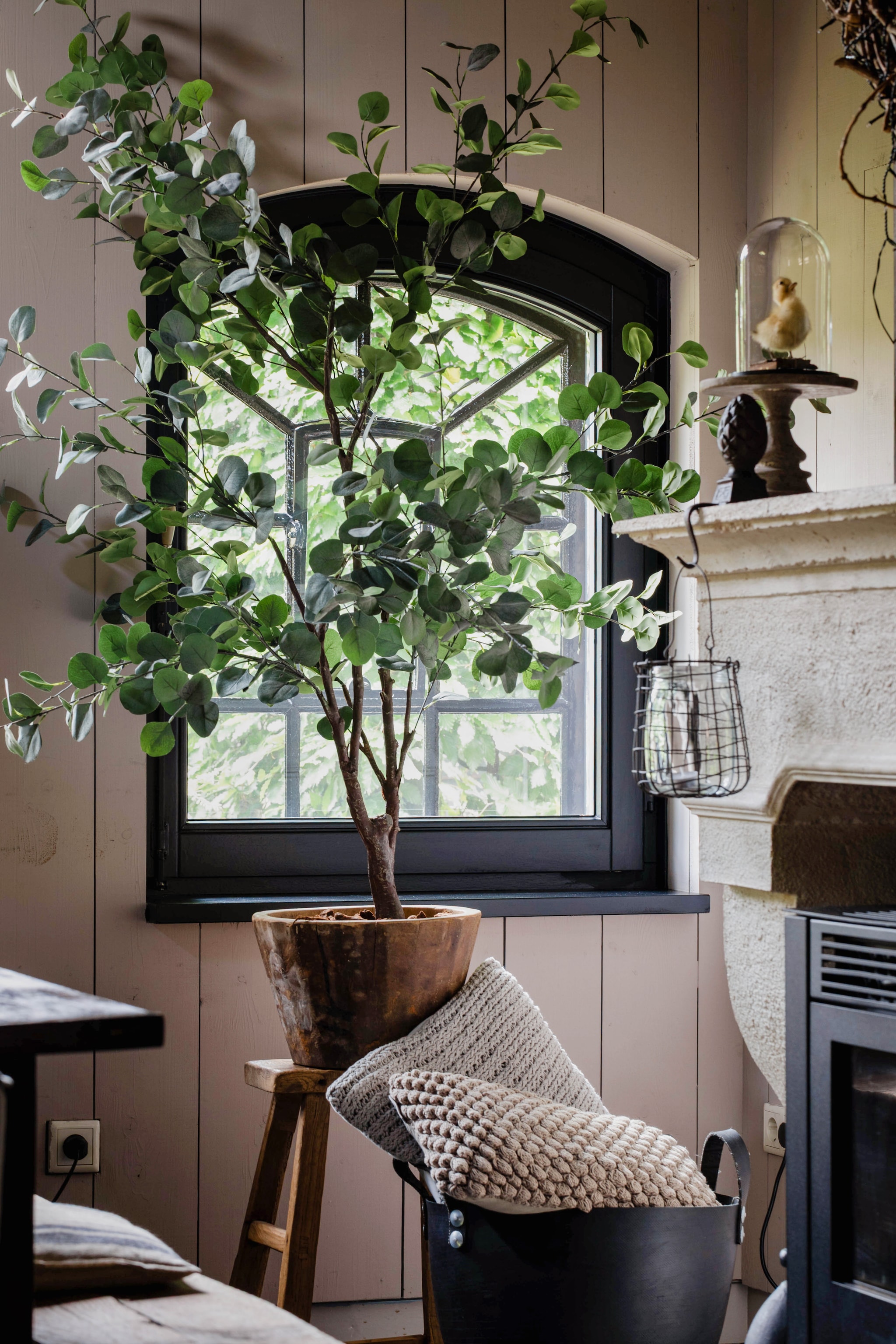 Houten pot, kunstplant en kussens ’t Hoogehuys. Mand Leen Bakker. De schouw maakte Claudia’s vader. vtwonen Landelijk 9-2025 | Fotografie Corine Hoge Bavel-Jansen