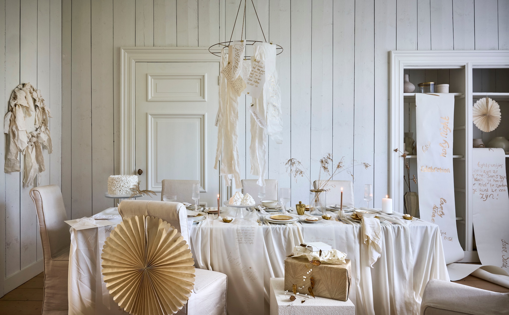 vtwonen decoratiering, metaal, goud, 60x61 cm (Øxh) € 29,95, kommen, porselein, wit-goud, 18 cm (Ø), set van 4 € 39,-, borden, porselein, wit-goud, 25,5 cm (Ø), set van 2 € 25,-, pastabord, porselein, wit-goud, 25,5 cm (Ø), set van 2€ 25,50, serviesset, porselein, wit-goud, 16-delig € 125,-, bord, porselein, goud, 12 cm (Ø), set van 4 € 24,95,-, ontbijtbord, porselein, goud, 20 cm (Ø) set van 2 € 26,95, theetip, porselein, goud, 7 cm (Ø), set van 4 € 14,95, vaas, glas met metalen deksel, 12,5x19 cm (Øxh) € 34,95, champagneglas, coupe, glas met gouden rand, 300 ml € 10,95, wijnglas, glas met gouden rand, 400 ml € 10,95, champagneglas, flûte, glas met gouden rand, 230 ml € 10,95, taartplateau m, geribbeld glas, 24,7x12 cm (Øxh) € 39,95,  taartplateau l, geribbeld glas, 29,6x18 cm (Øxh) € 49,95, kandelaars, keramiek, wit, 5,6x6 cm (Øxh) € 12,95, kandelaars, keramiek, wit, 8x2,5 cm (Øxh) € 14,95(shop.vtwonen.nl). Vintage stoelen Rivièra Maison (marktplaats.nl). Ikea rol teken-papier Måla € 3,19 (ikea.com). H&m Home bord met bloemafdruk, keramiek € 9,99 (hm.com). MrsBloom ster, papier, beige, 50 cm (Ø), ster, papier, beige, 30 cm (Ø), slinger messing blaadjes en kralen, 170 cm (l), alles prijs op aanvraag (mrsbloom.nl). Zara Home bijzettafel, kubus, wit, 40x40x45 cm (lxbxh) € 199,- (zarahome.com). Søstrene Grene stompkaars, wit 10 cm € 1,68 (sostrenegrene.com). Overig privébezit.Pas met zo’n prachtige hanger goed op met kaarsen op tafel. Ga eventueel voor ledkaarsen, die zijn tegenwoordig niet meer van echt te onderscheiden. vtwonen landelijk 11-2025 | styling Sanne Ketelaar | fotografie Alexander van Berge