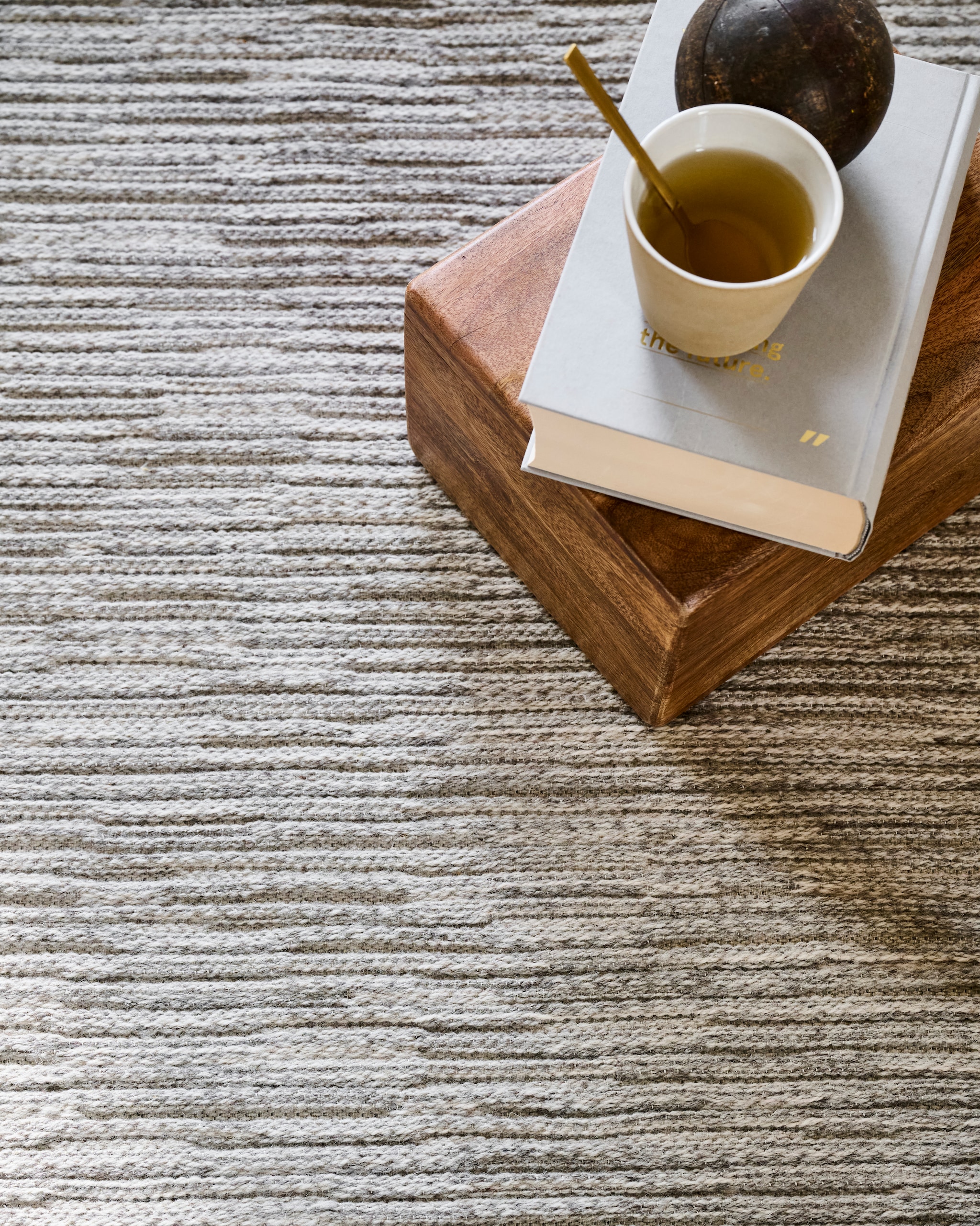 vtwonen vloerkleed Nature Cord, 100% kwaliteitswol, grijs melé, 160x230 cm € 449,-, 200x290 cm € 719,- en 240x330 cm € 975,-.M.m.v. householdhardware.nl (lamp, mand), urbannatureculture.com (houten kistje, kussens), casagitane.com (lantaarn). vtwonen 10-2025 | styling Sanne Ketelaar, Marlies Does | fotografie Sjoerd Eickmans, Peggy Janssen