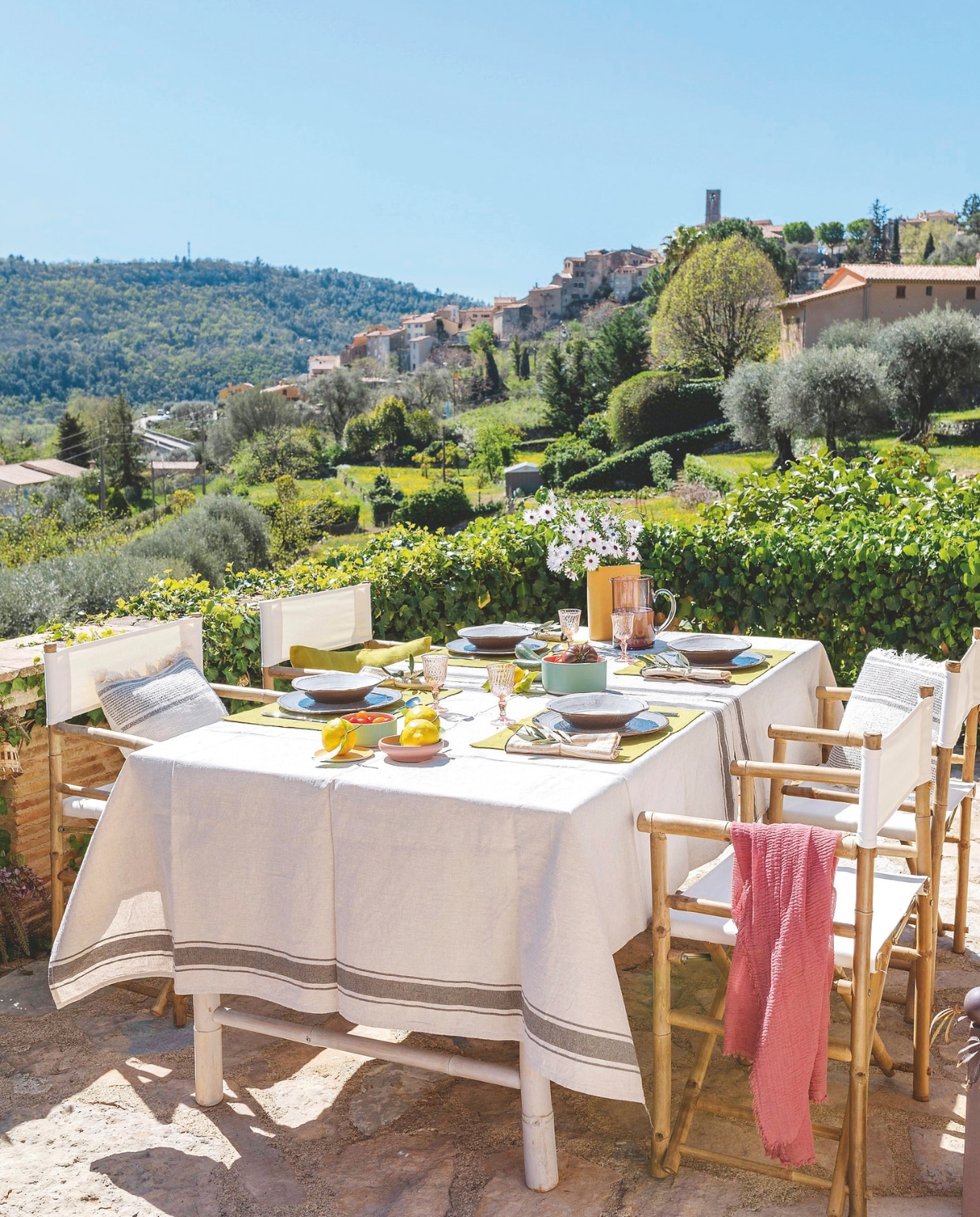 Lunch met uitzicht op het middeleeuwse dorp Le Bar-sur-Loup. Tafelkleed Ikea. Vaas en servies Jars Céramistes. Kussens en placemats La Trésorerie. Vergelijkbare stoelen Sklum en VidaXL. vtwonen landelijk 7-2025 | styling Elen Pouhaer | fotografie Marta Puglia