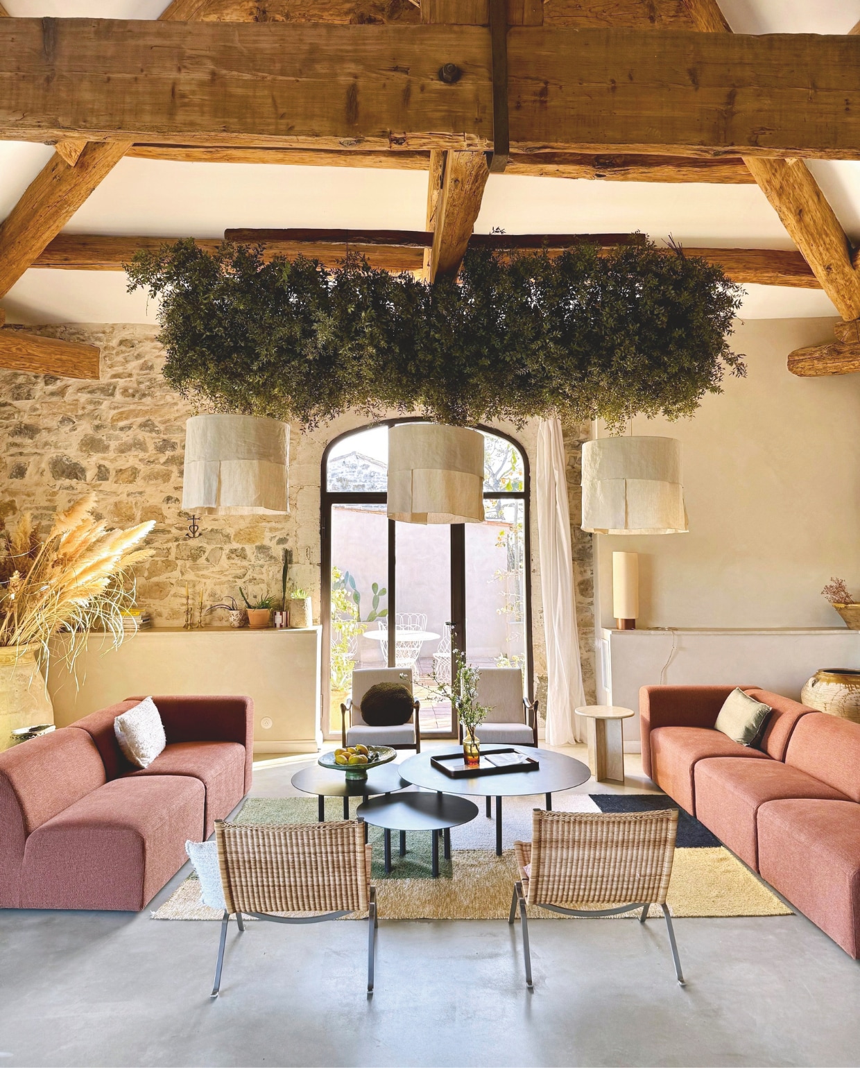 Banken by Sidde, metalen salontafels zelfgemaakt, katoenen kleed Saudade Design. Linnen hanglampen Studio Echo. Fauteuils Rua Madeira, rotan stoelen PK22 van Poul Kjaerholm voor Fritz Hansen. Travertin bijzettafel Talka. Groene installatie gemaakt van schijnhulst. Maatwerk stalen kozijnen L’Atelier Souriou in RAL-kleur 8019. vtwonen 07-2025 | fotografie Manon Ferra